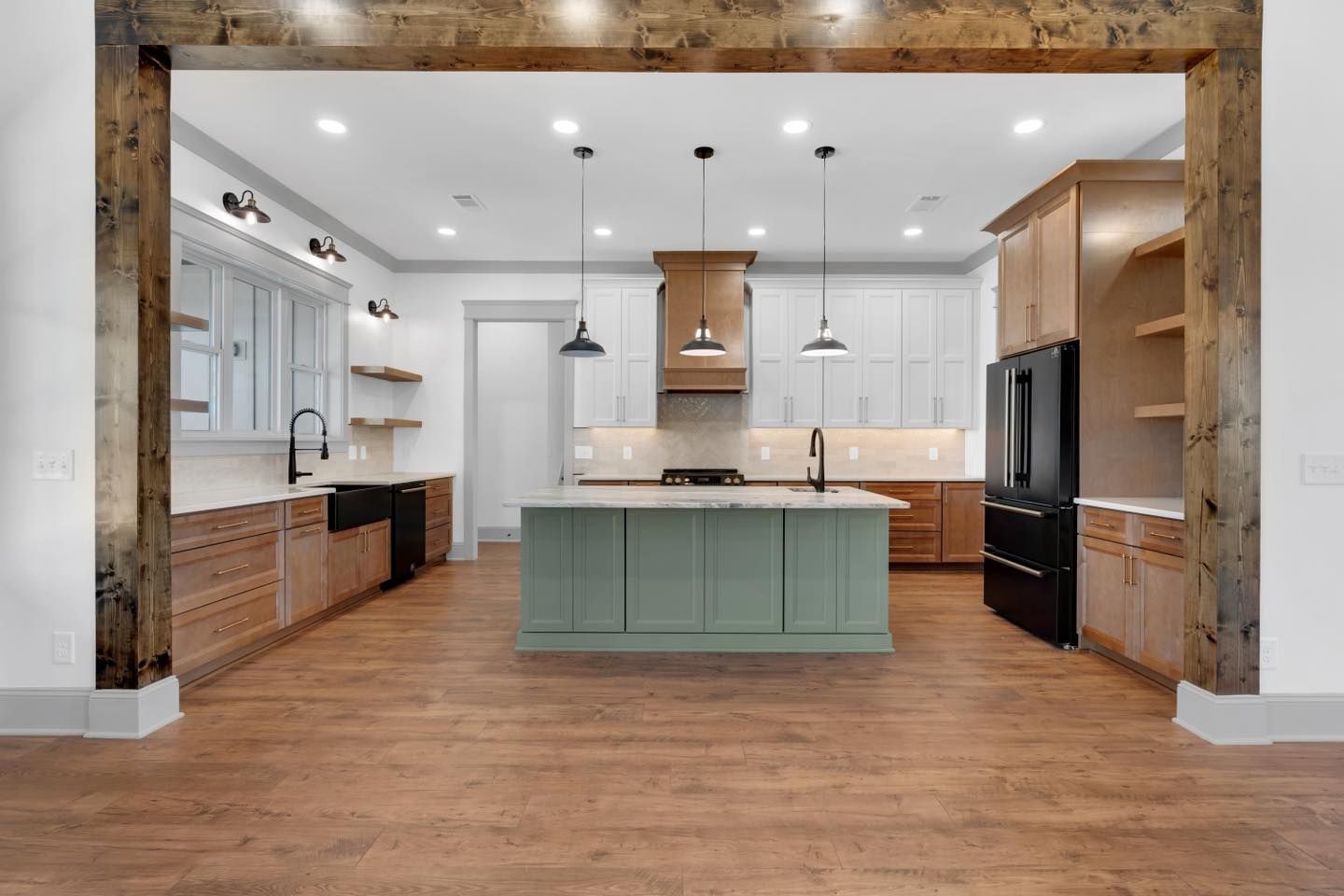 A kitchen with a green island and wooden floors