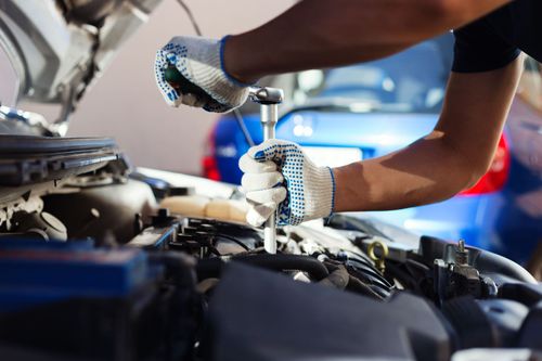 A man is working on the engine of a car.