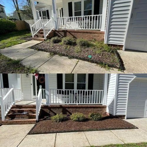 Front porch and walkway with new landscaping mulch and shrubs beside a gray house.