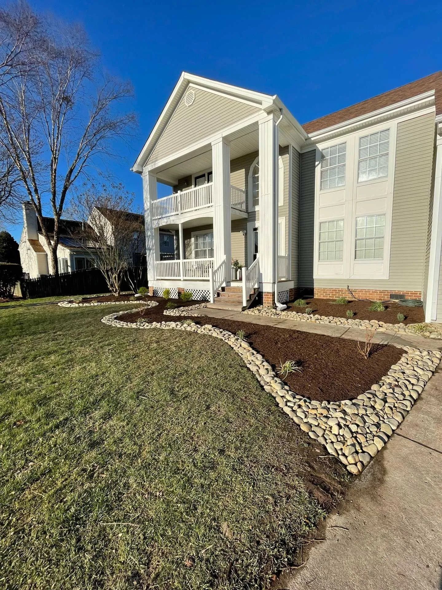 Apartment building with white columns, landscaped lawn, and blue sky on a sunny day