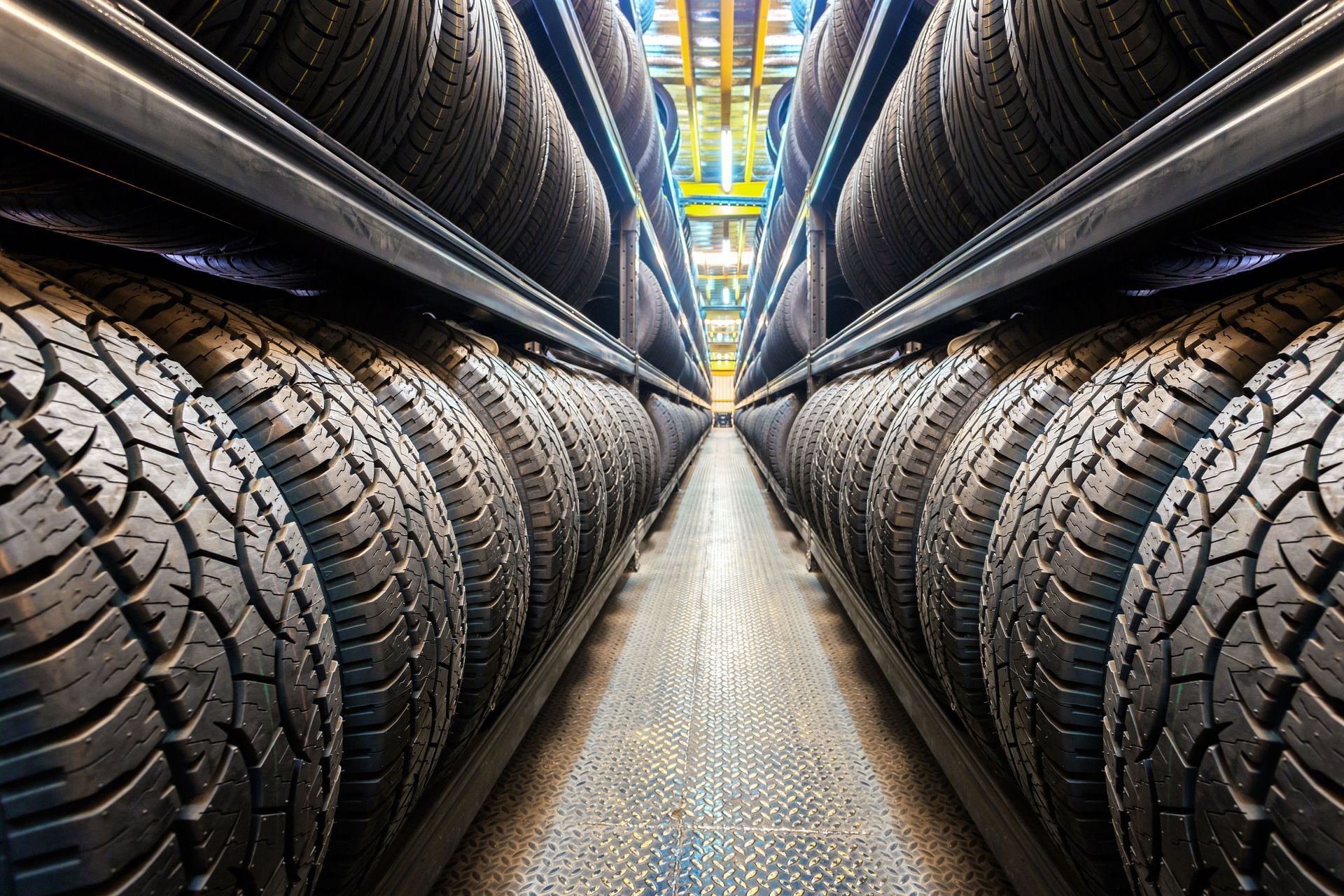 Rows of new tires stacked on shelves in a warehouse.