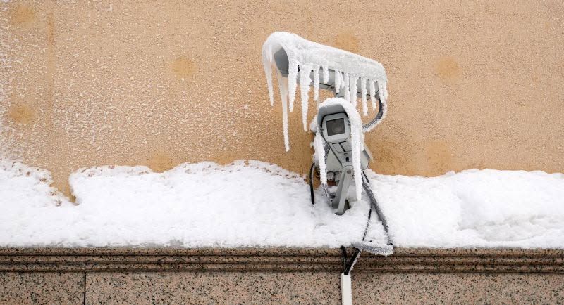 Icy outdoor electrical outlet with icicles hanging from it on a snowy ledge