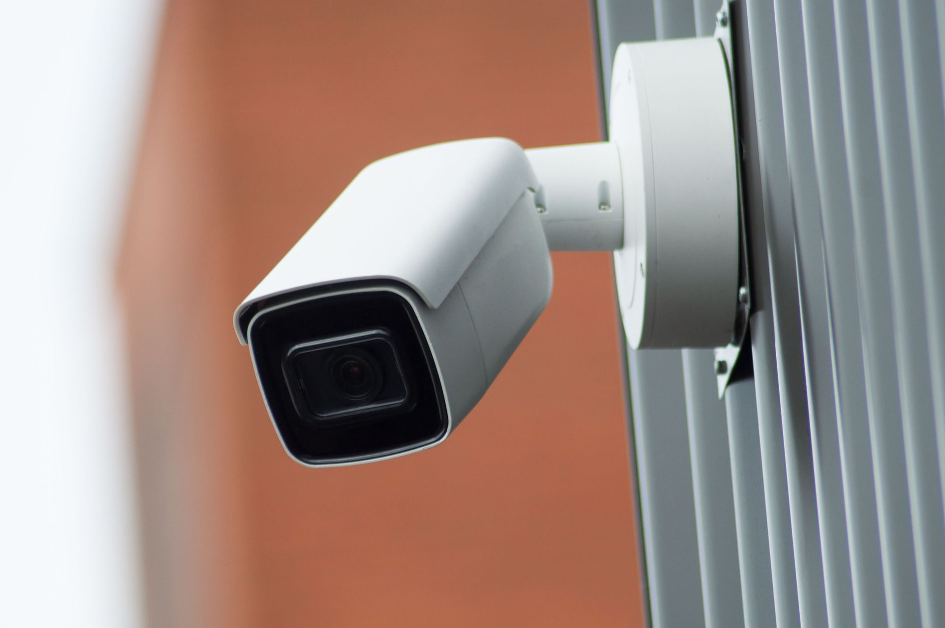 White security camera mounted on a wall, angled outward