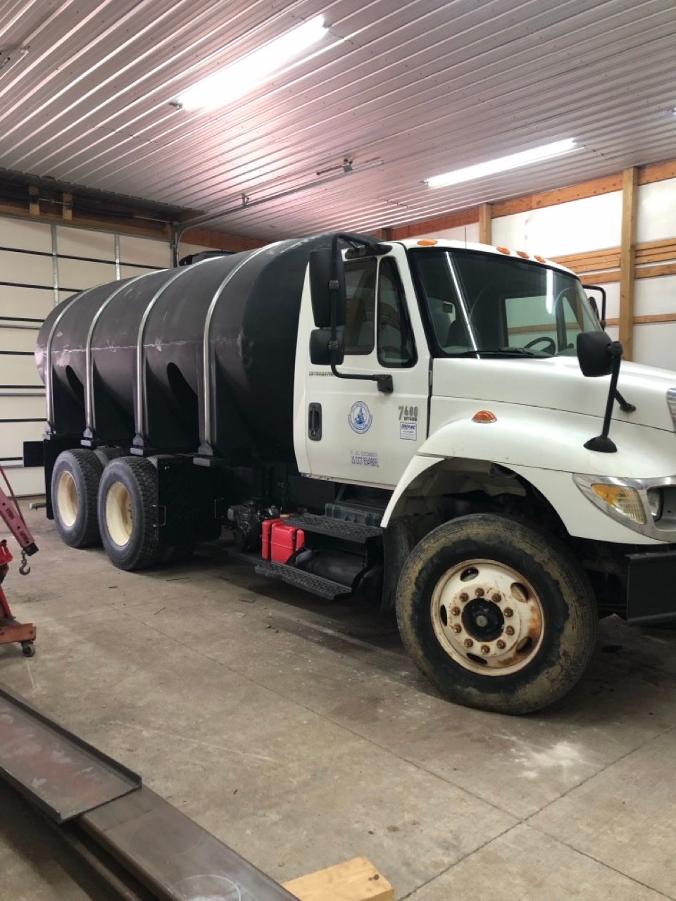White and black dump truck parked inside a garage, side view
