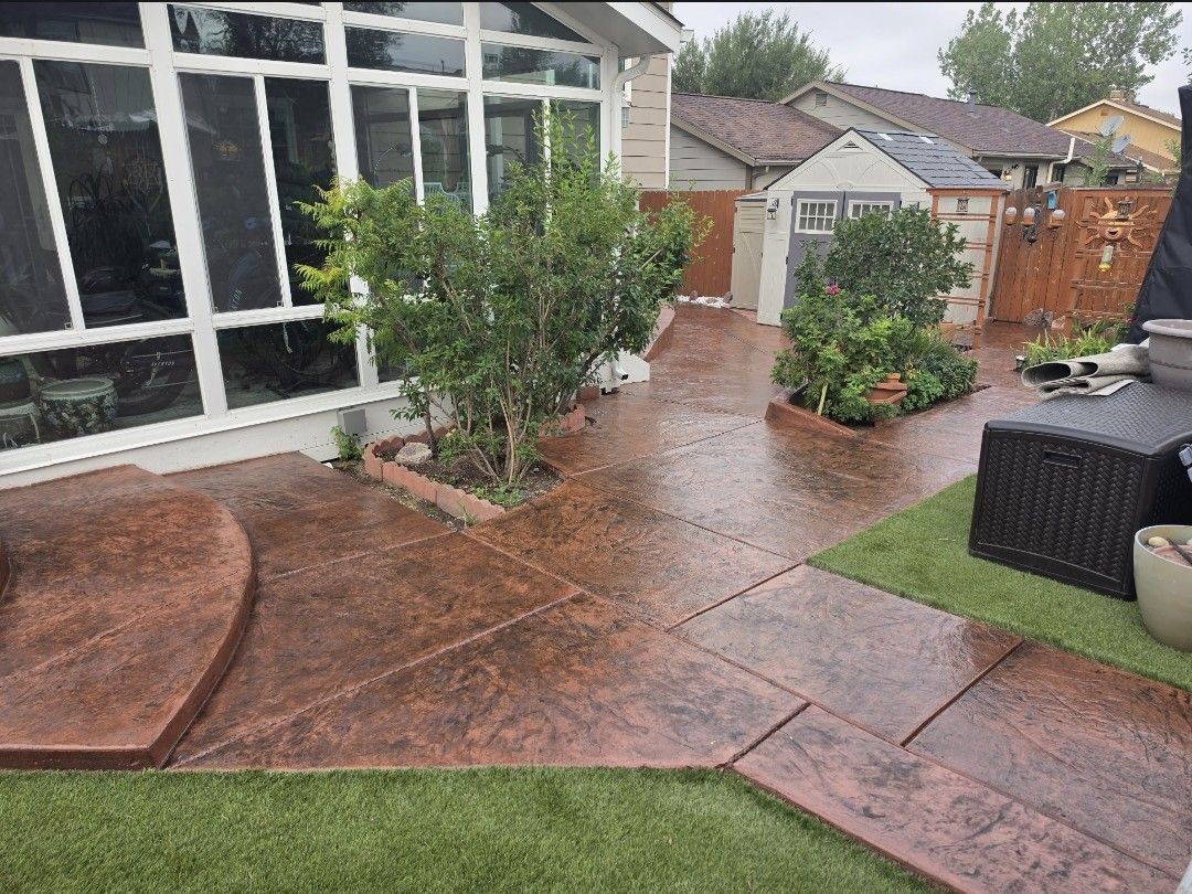 Rainy backyard patio with stamped concrete, potted plants, and a glass-enclosed porch