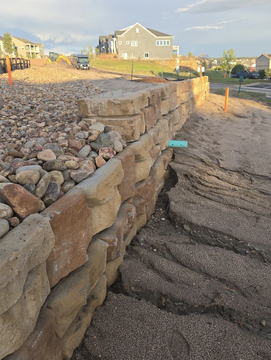 Rock retaining wall beside a gravel path at a new residential construction site.