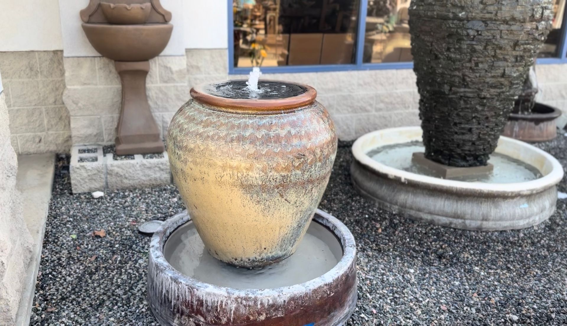 A fountain in a pot is surrounded by other fountains.
