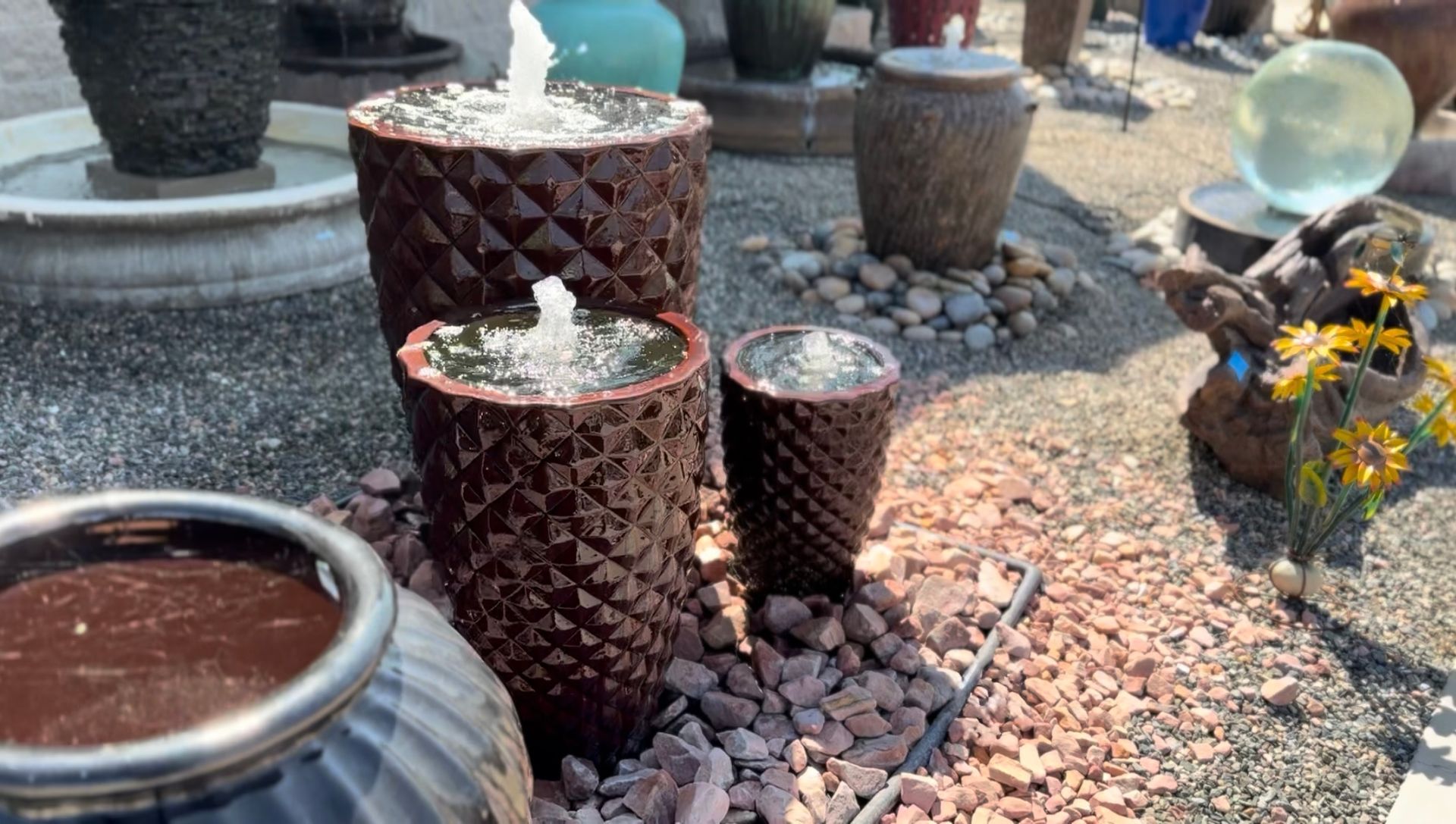 A fountain is surrounded by pots and rocks in a garden.