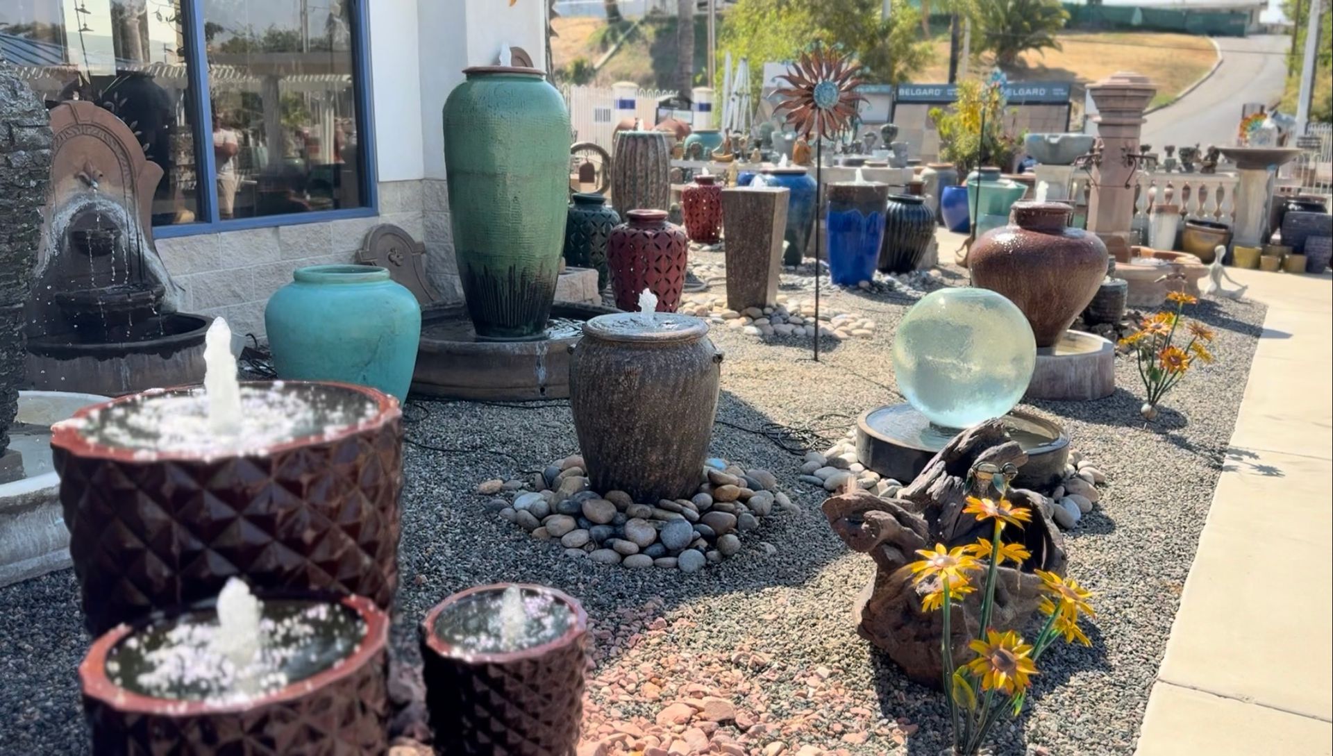 A display of potted plants and fountains in front of a building.