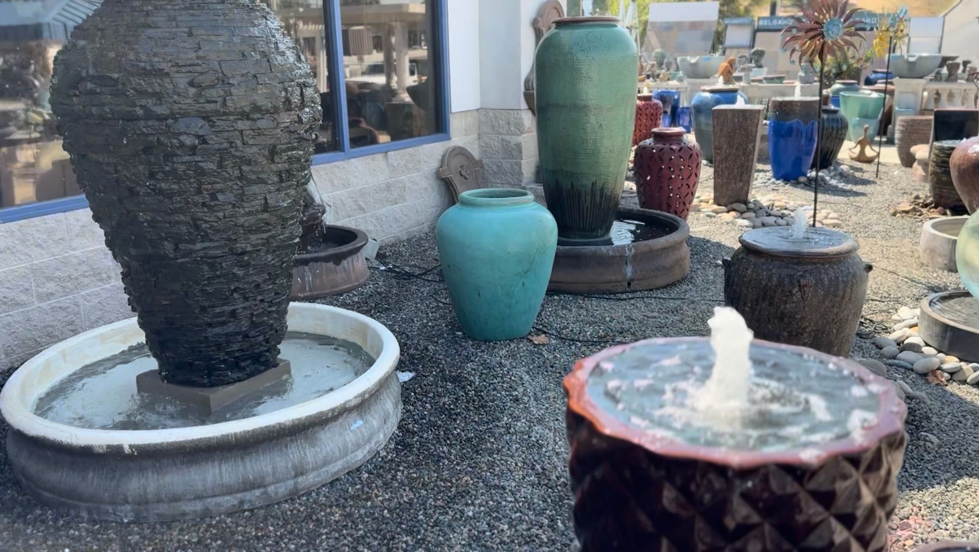 A fountain is surrounded by vases and pots in a garden.