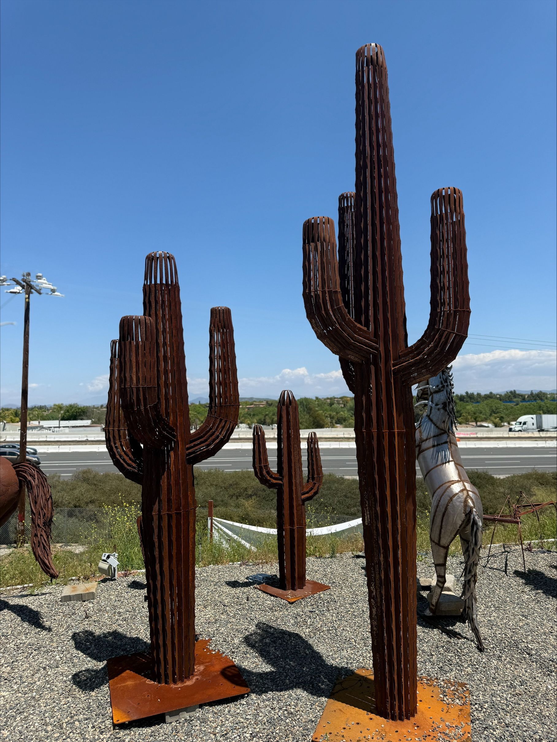 A group of cactus sculptures are sitting on top of a gravel field.