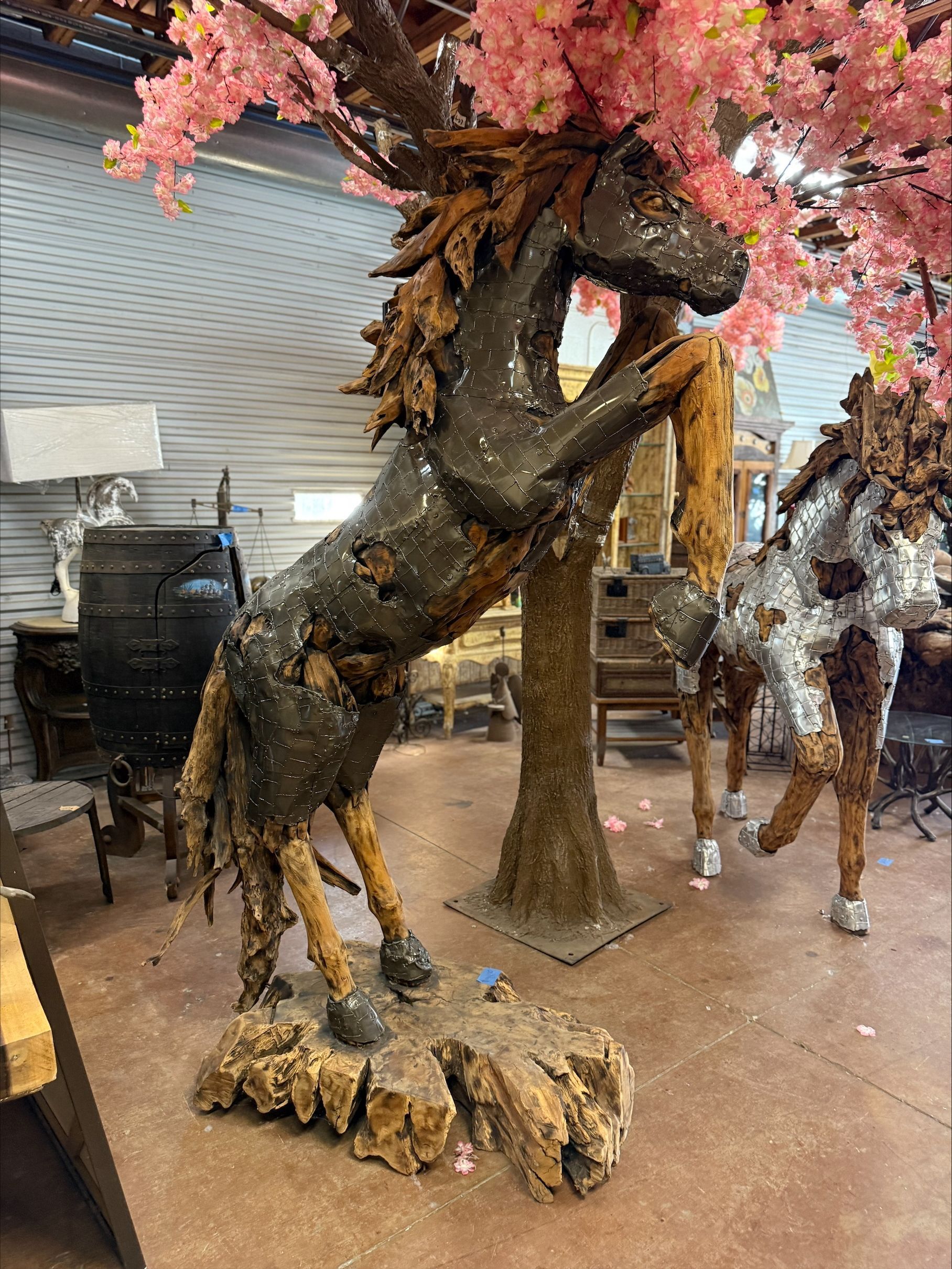 A statue of a horse standing next to a tree in a room.