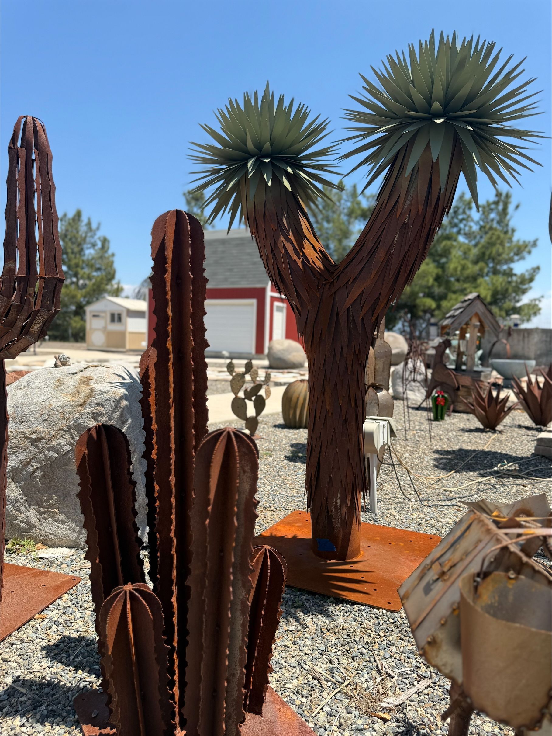 A bunch of cactus sculptures are in a gravel area