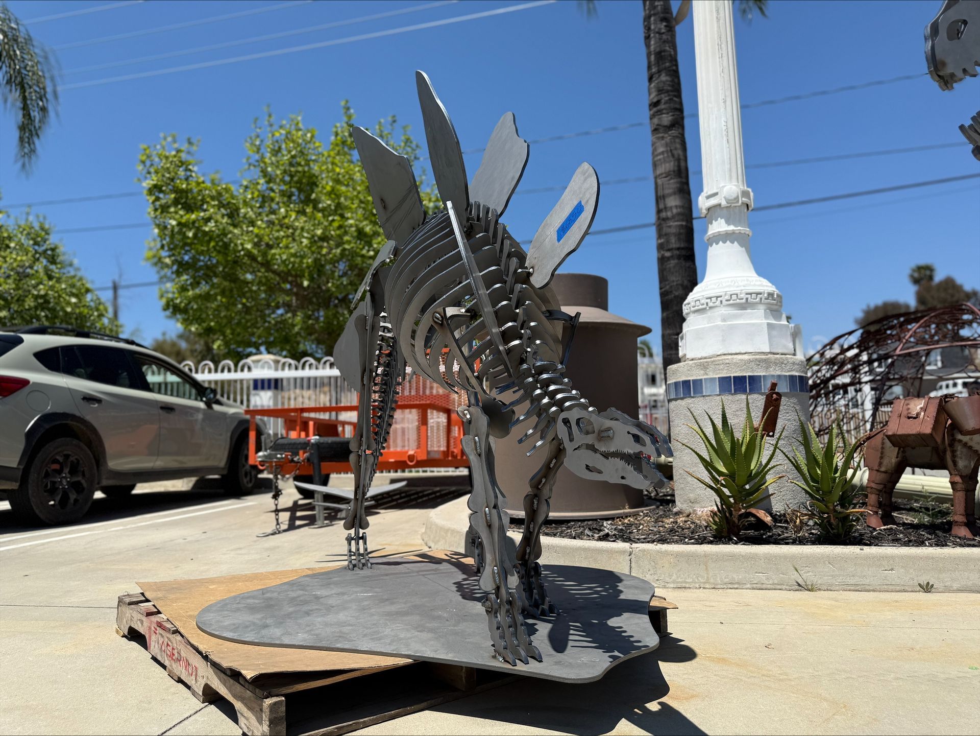 A statue of a dinosaur is sitting on a cardboard pallet.