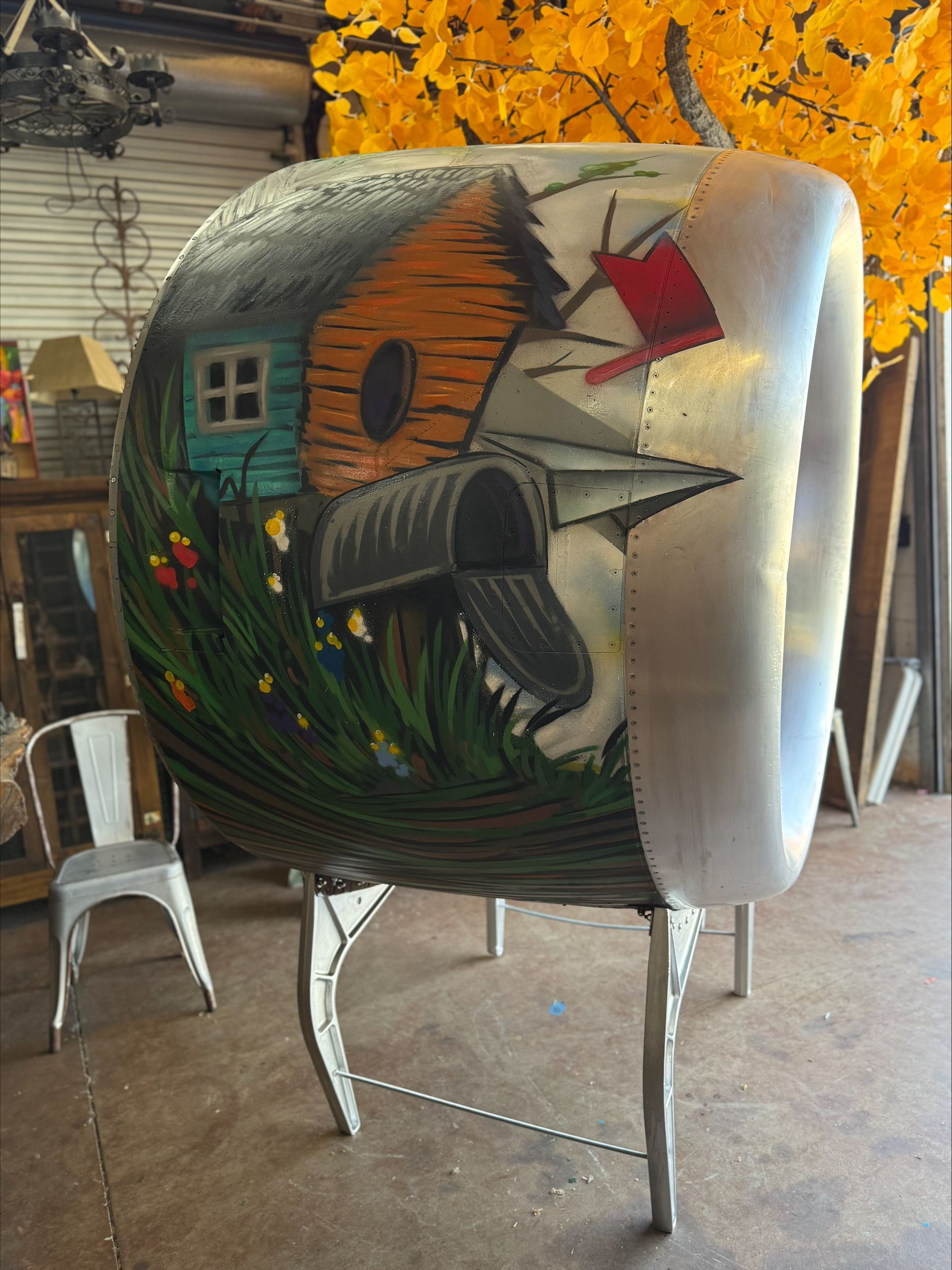 A painting of a birdhouse and mailbox on a piece of metal