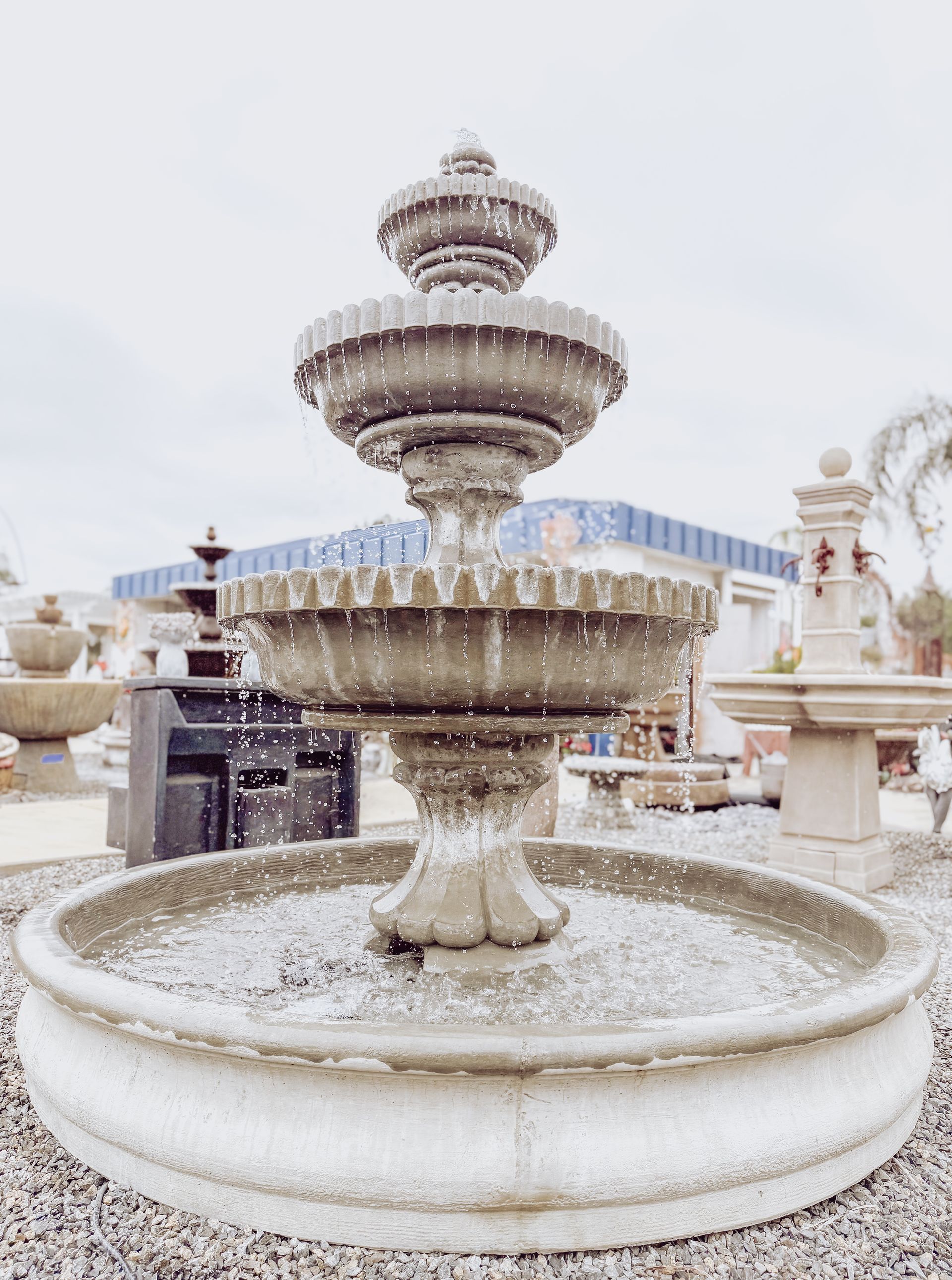 A large fountain is sitting on top of a gravel ground.