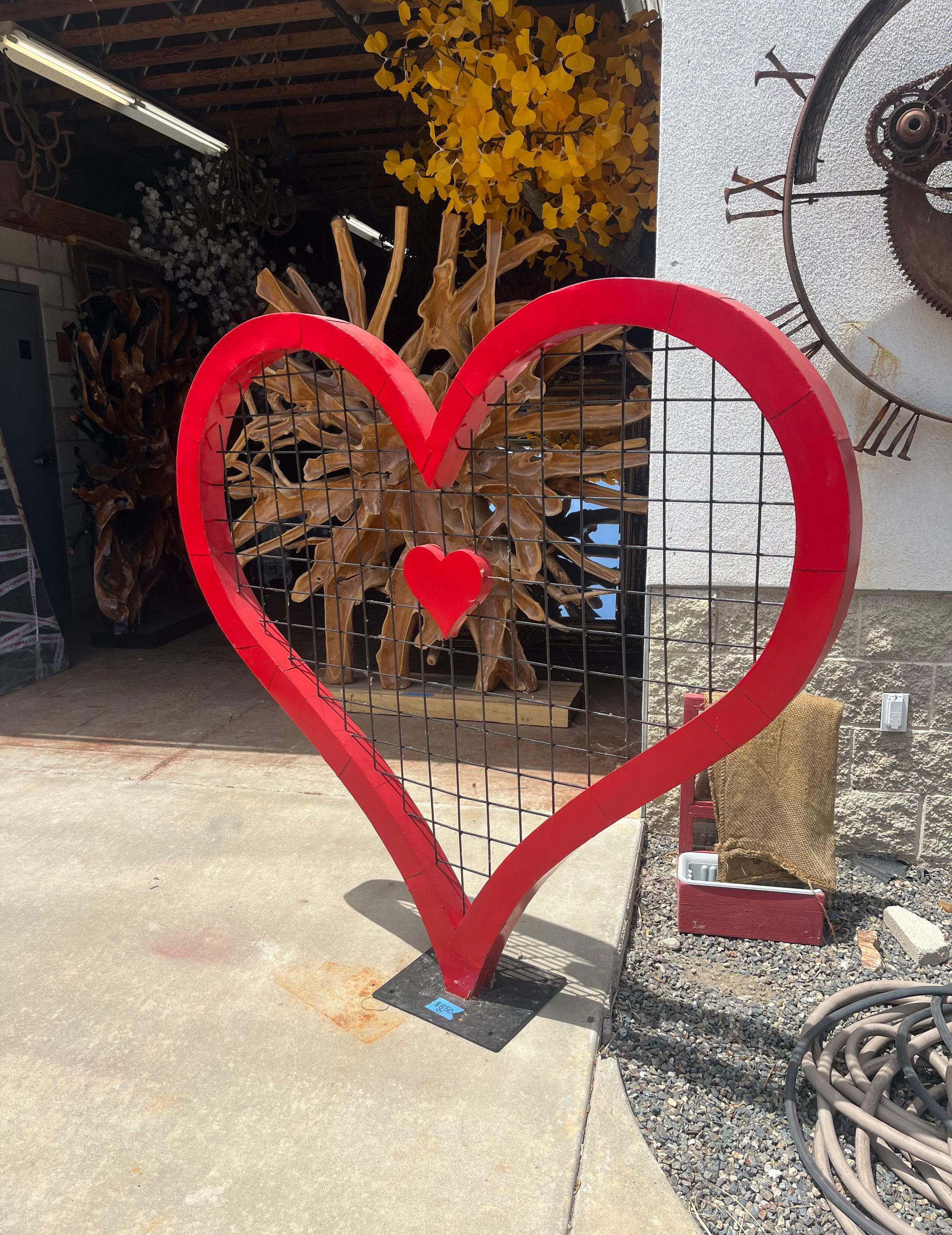 A large red heart shaped sculpture is sitting on the sidewalk in front of a building.