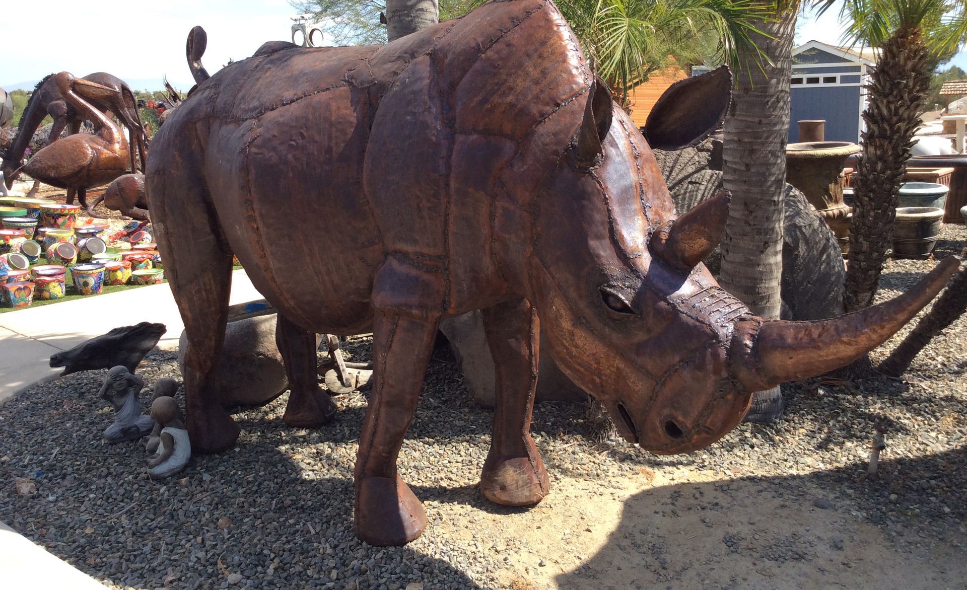 A large rhino statue is standing in the dirt