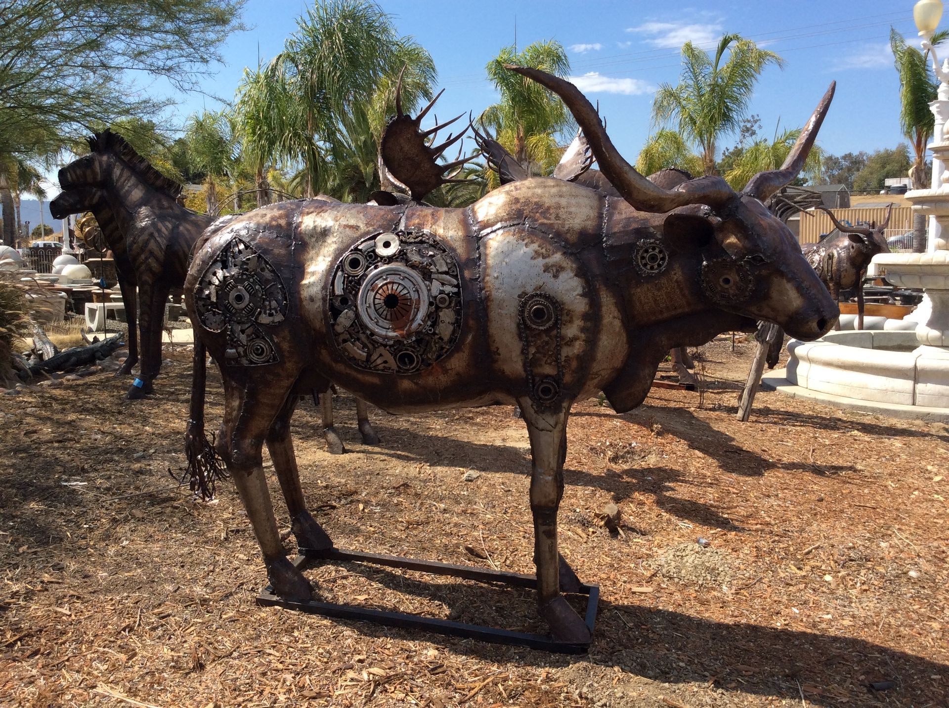 A statue of a bull with long horns is standing in the dirt