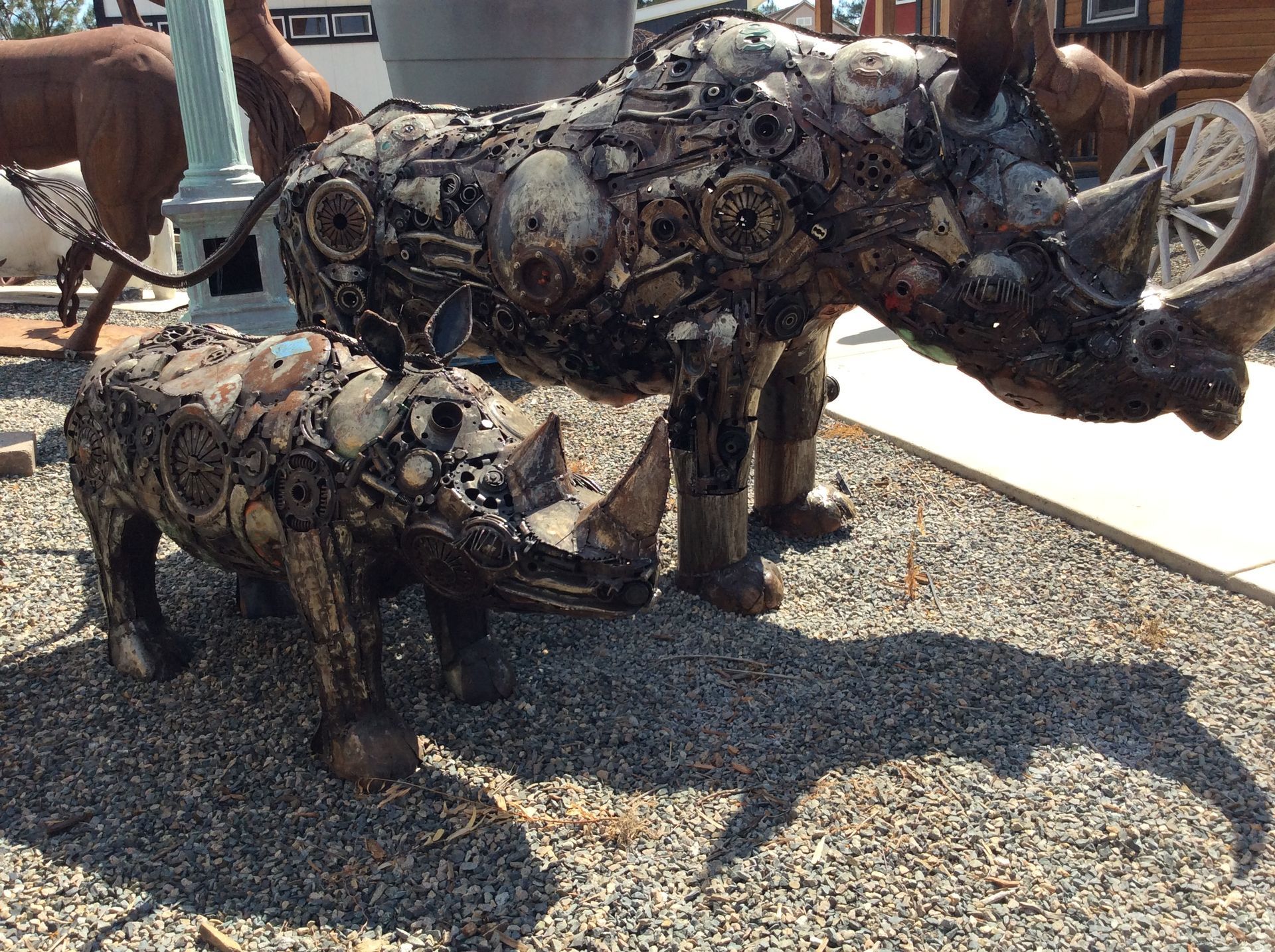 A statue of a rhinoceros and a baby rhinoceros made out of scrap metal.