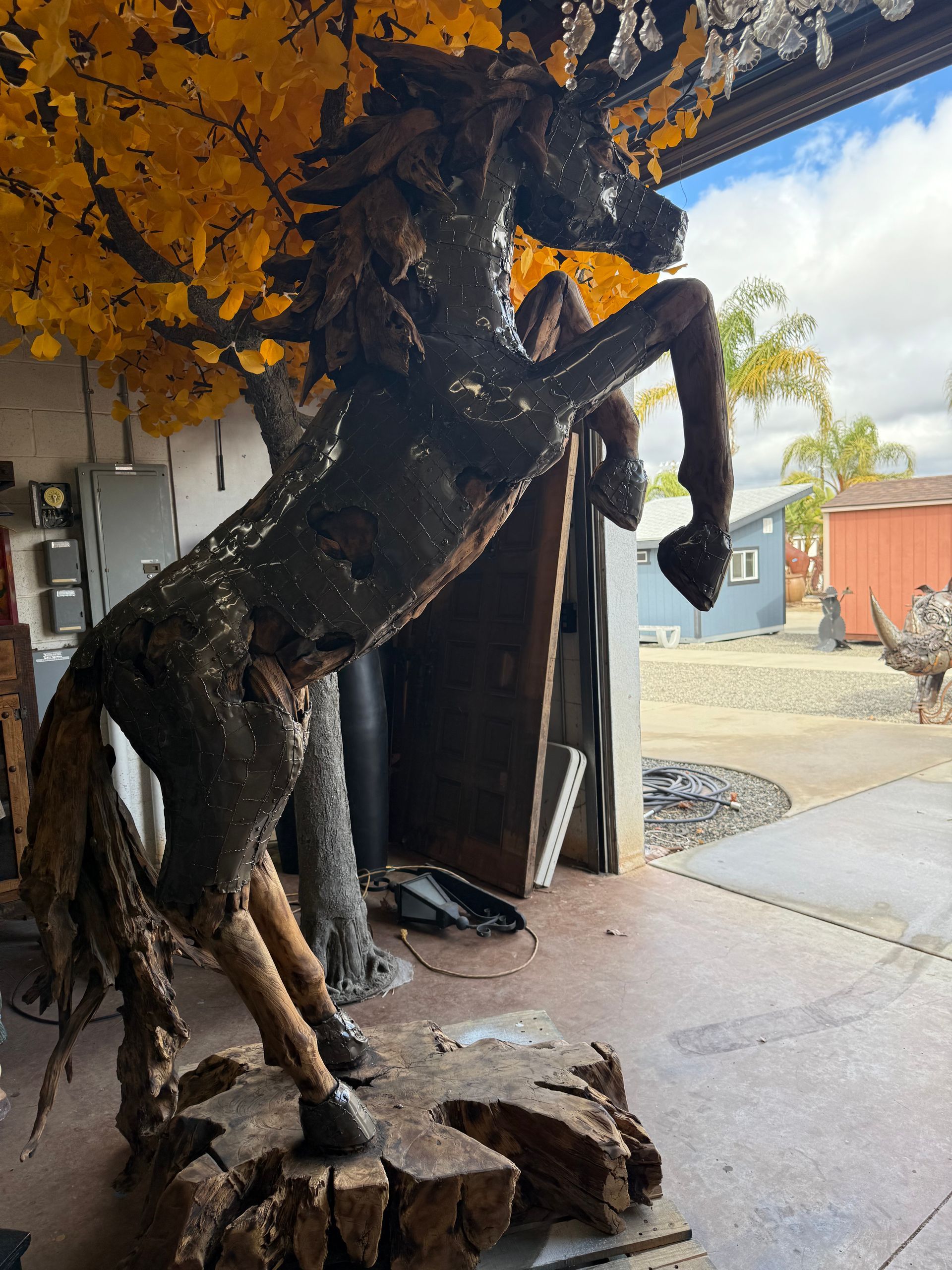 A statue of a horse standing on its hind legs under a tree