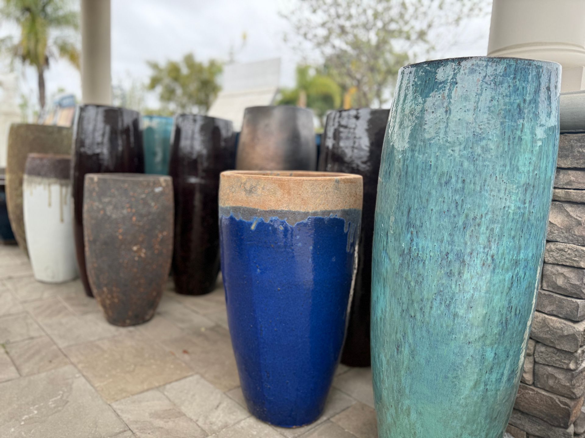 A row of blue and green pots are sitting on a tiled floor.