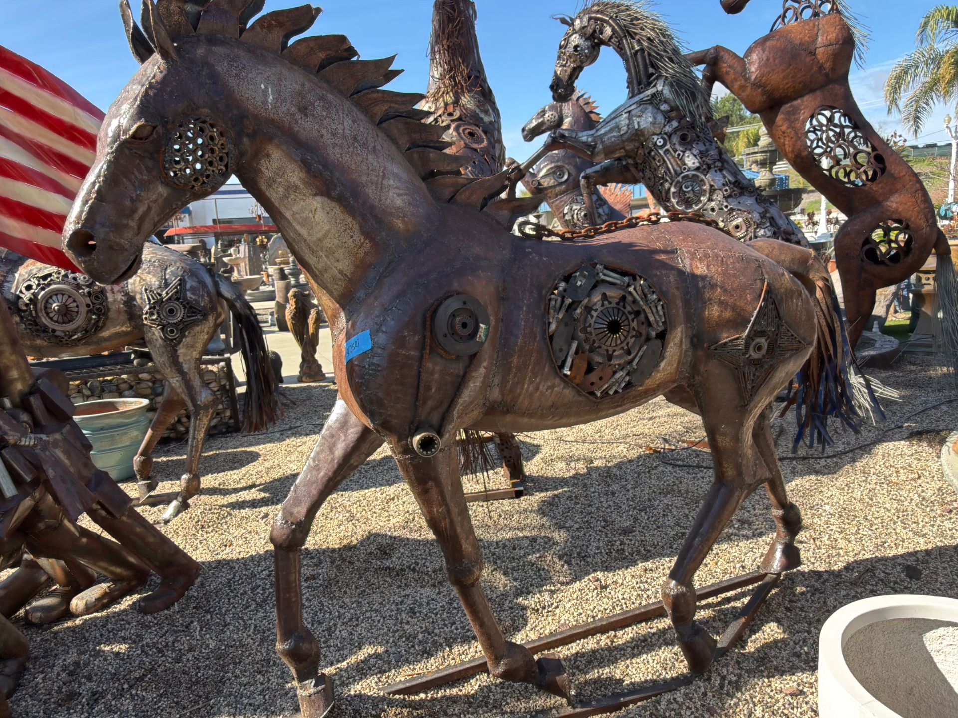 A statue of a horse made out of metal is standing in the dirt.
