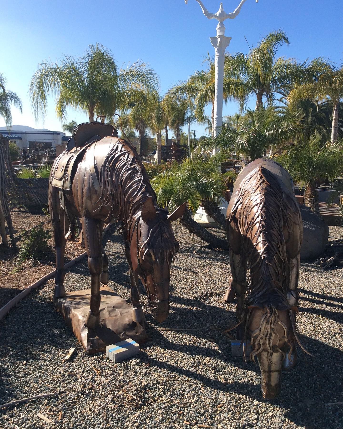 A statue of two horses standing next to each other on gravel.