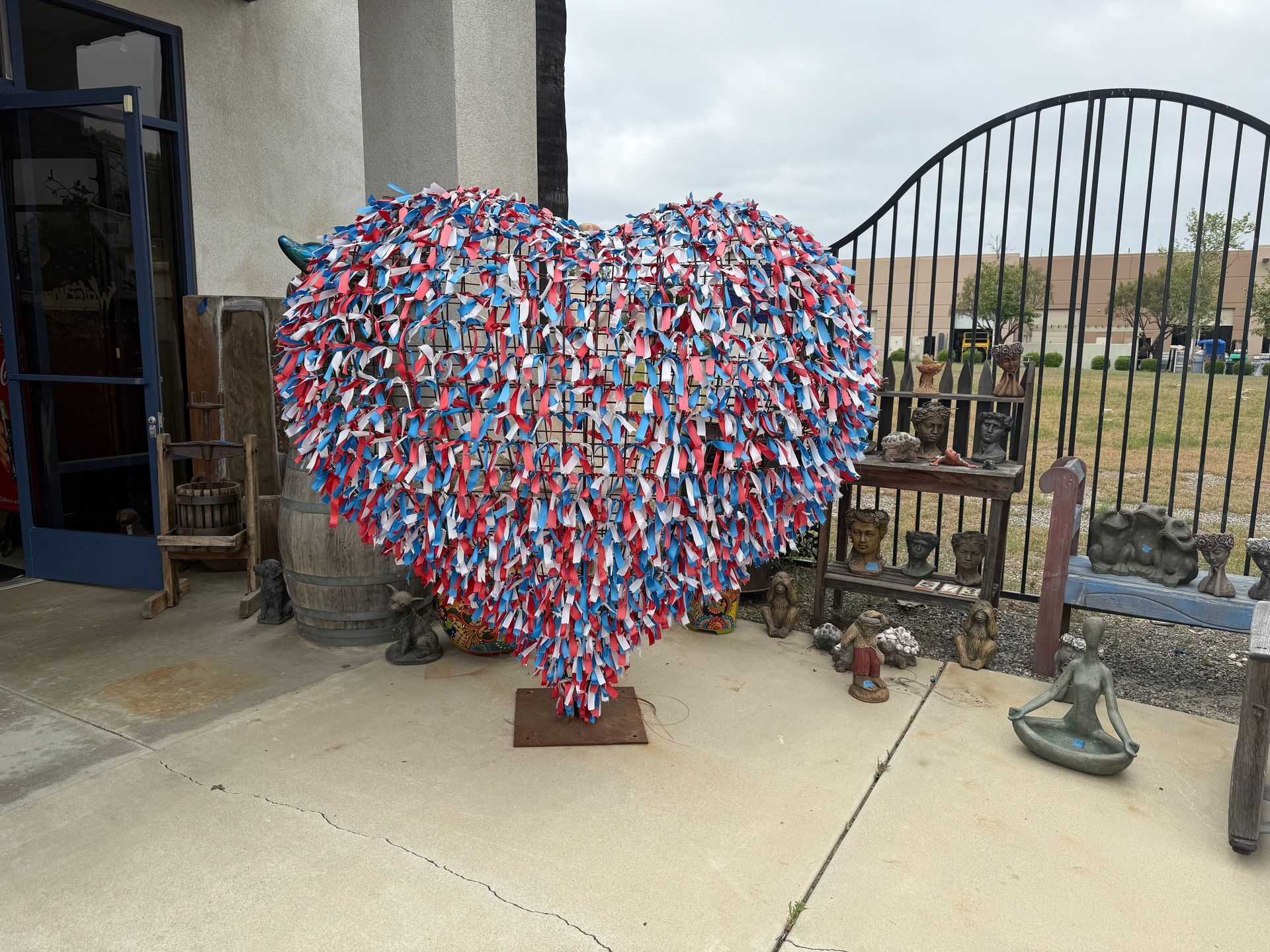 A large heart made of flags is sitting on the sidewalk in front of a building.