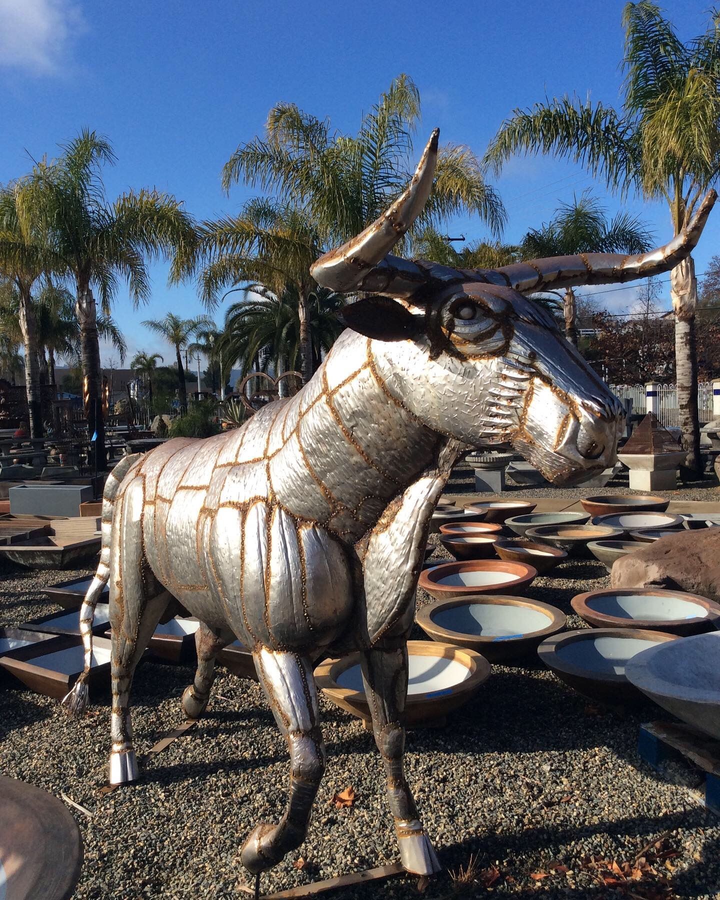 A statue of a bull is standing in a gravel area