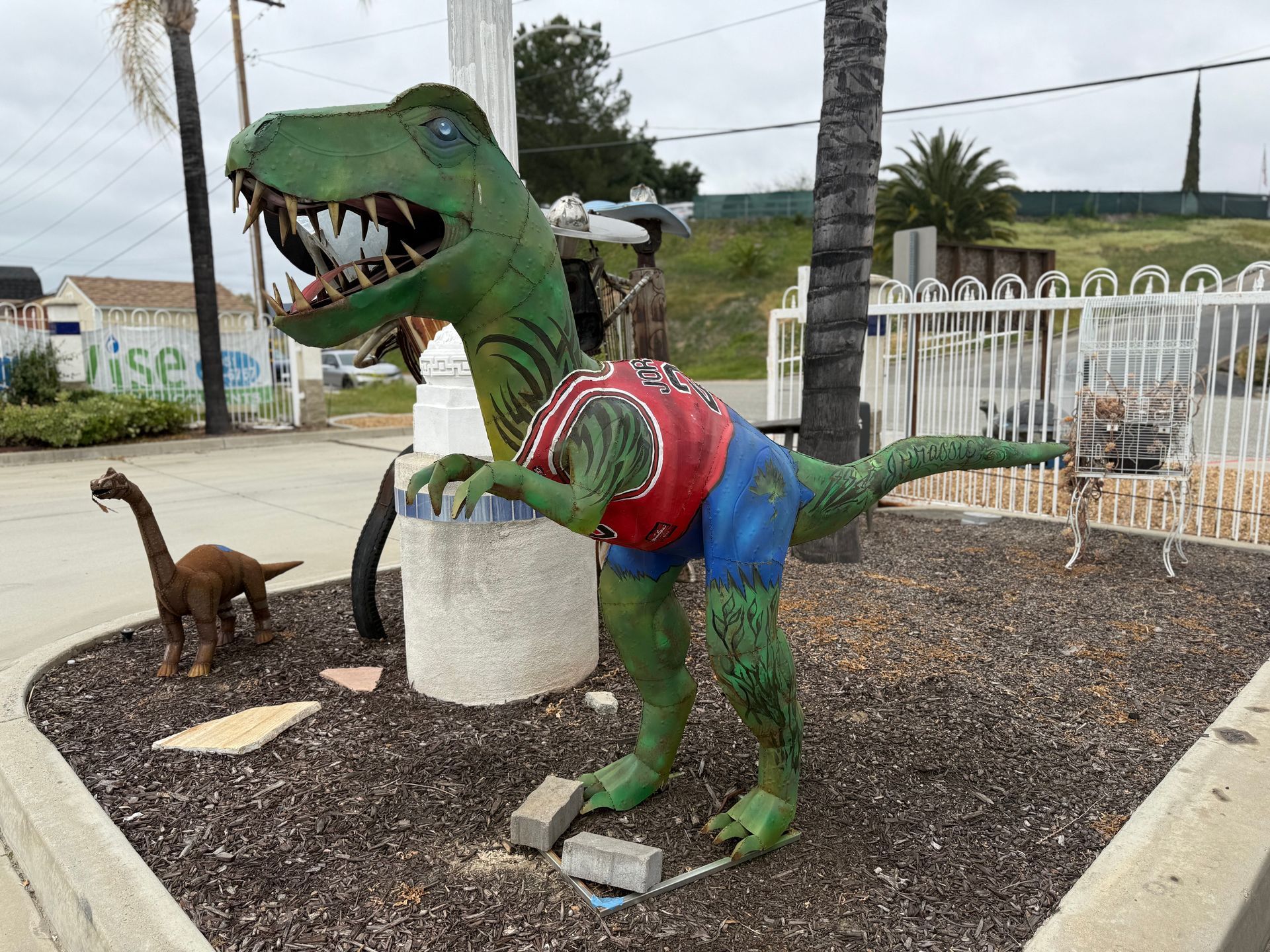 A statue of a dinosaur wearing a shirt and shorts
