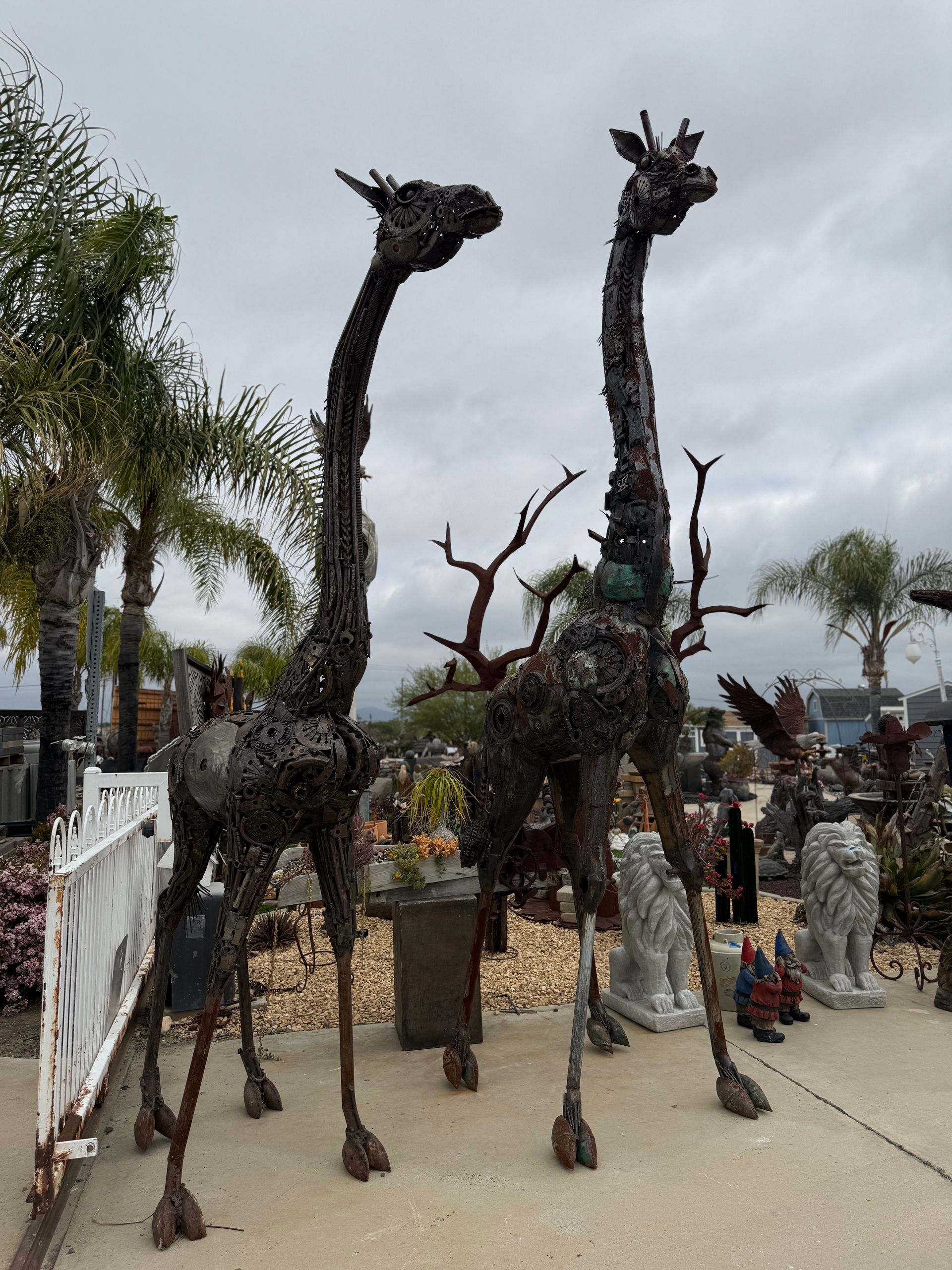 Two giraffe statues are standing next to each other on a sidewalk.