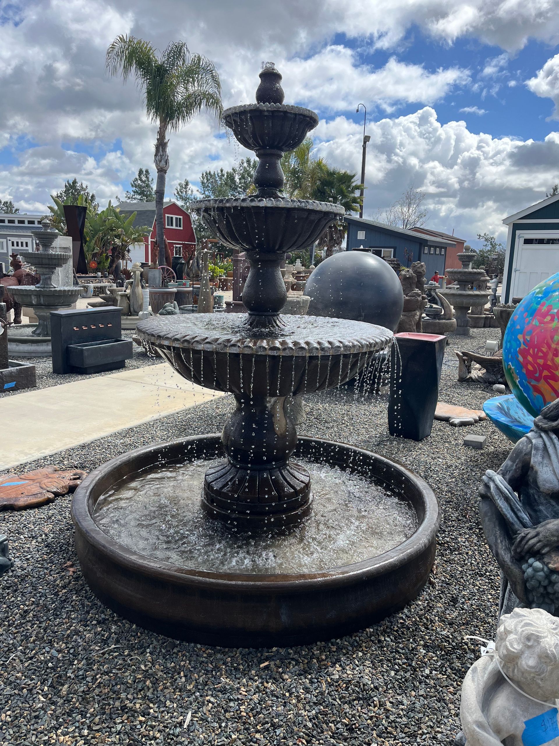 A large fountain is sitting in the middle of a gravel area.