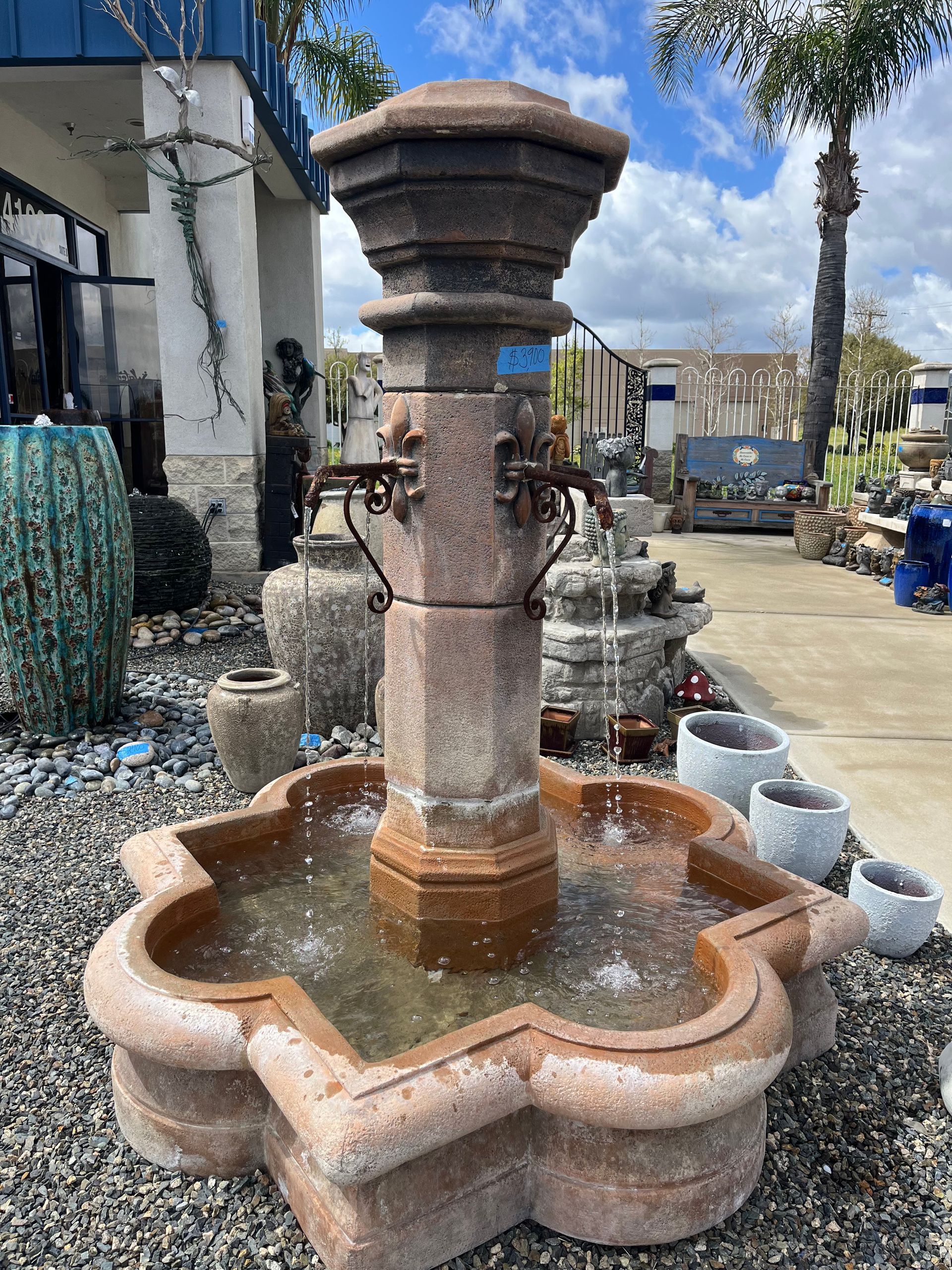 A fountain is sitting on top of a pile of gravel in front of a building.
