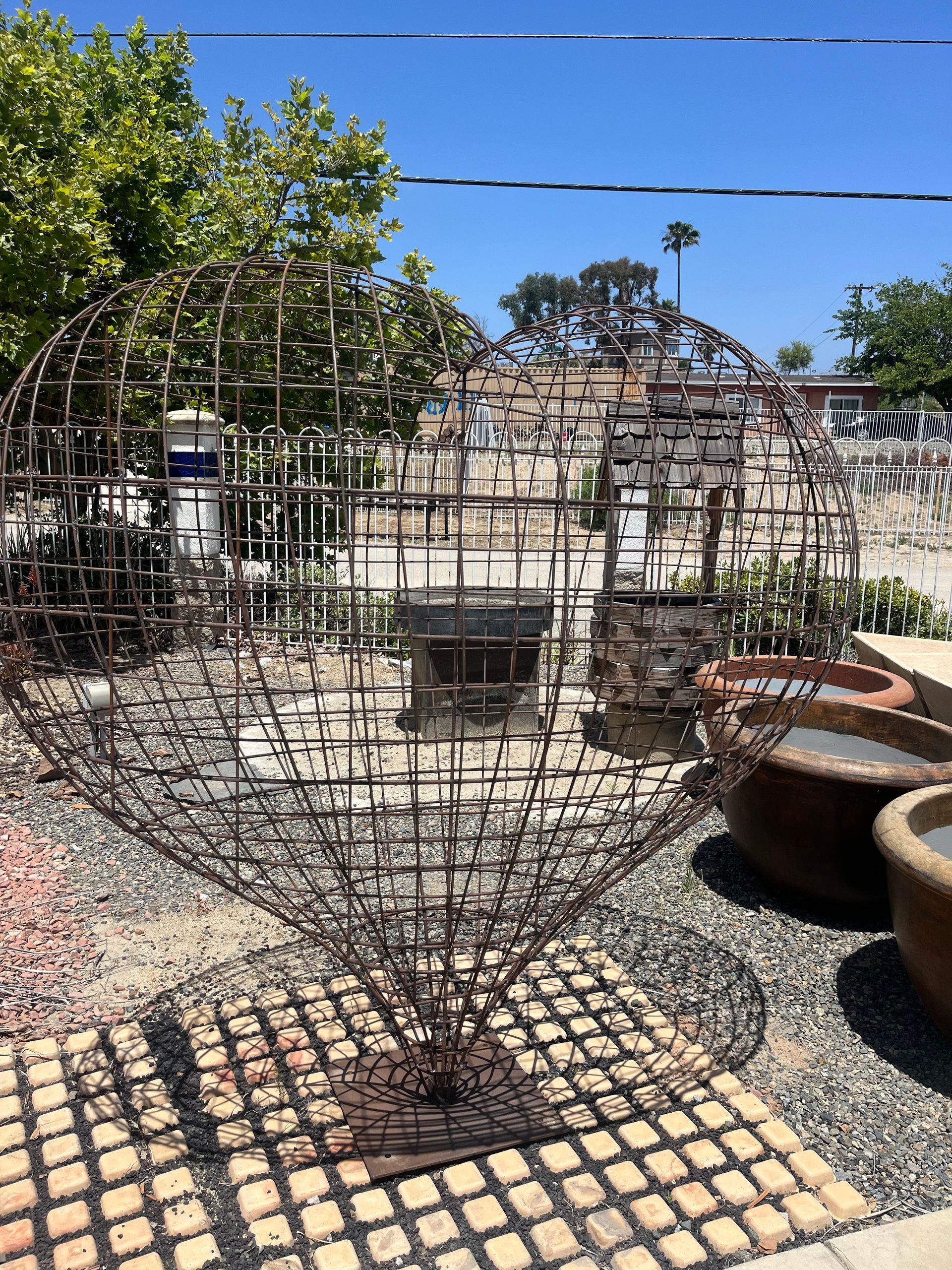 A large metal sculpture is sitting on top of a brick floor in a garden.
