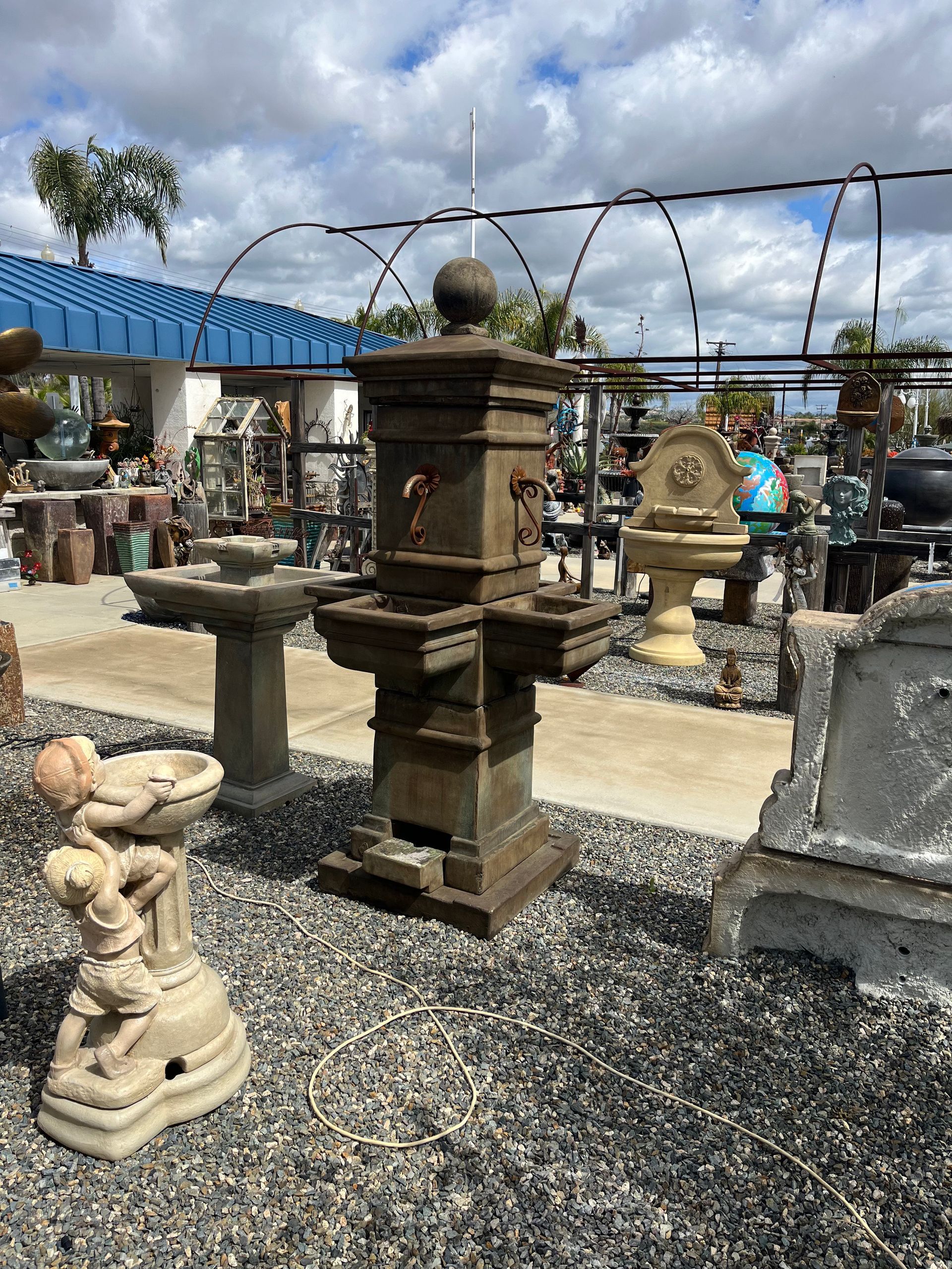 A fountain is sitting in the middle of a gravel yard.
