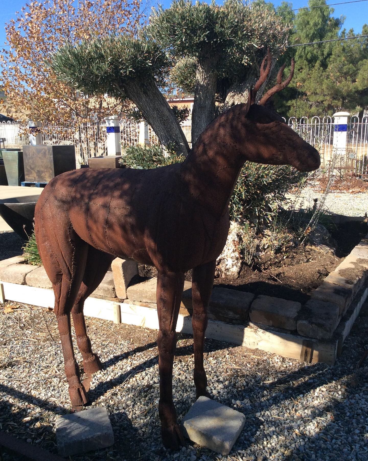 A statue of a deer is standing in a gravel area
