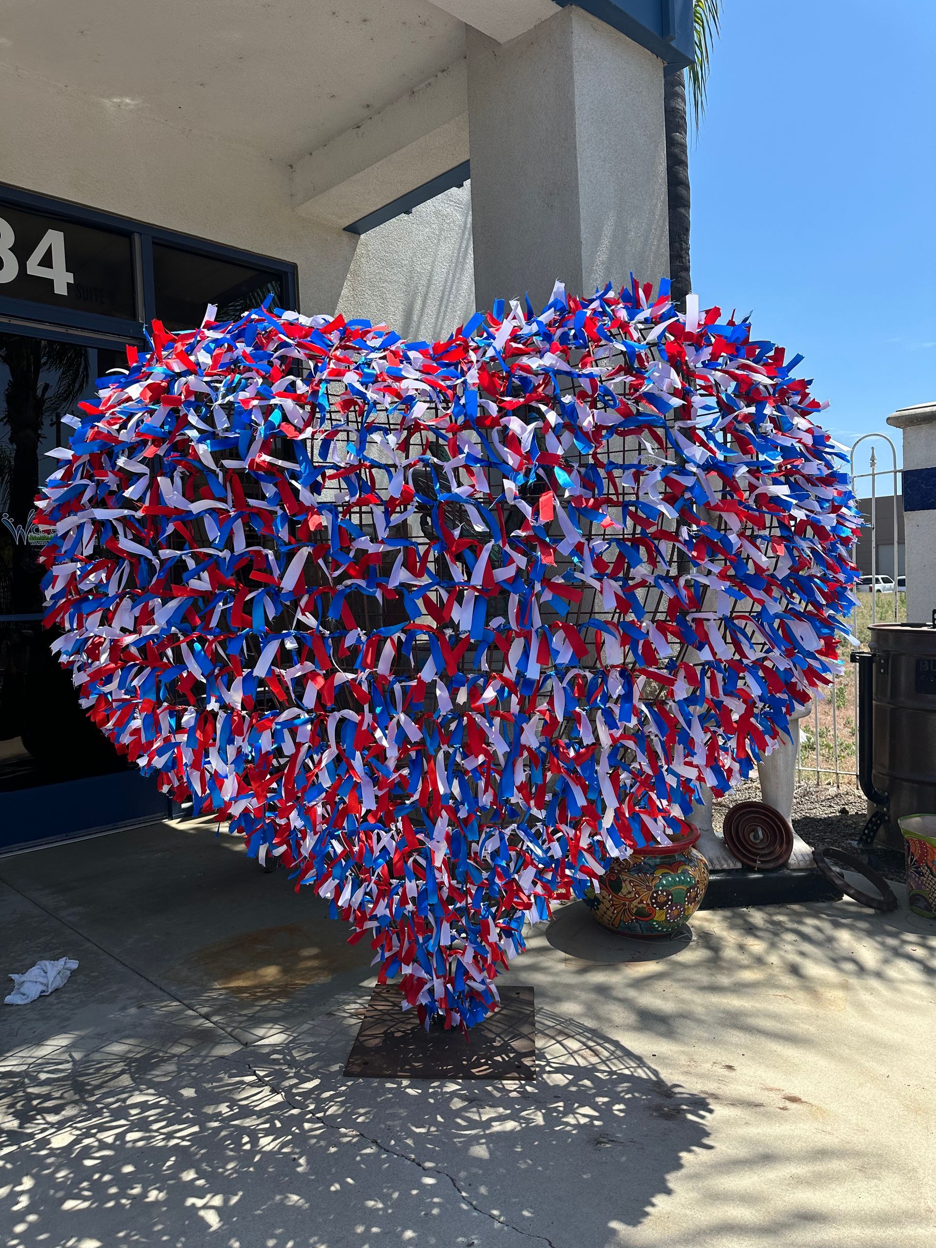 A large heart made of red , white and blue confetti is in front of a building.