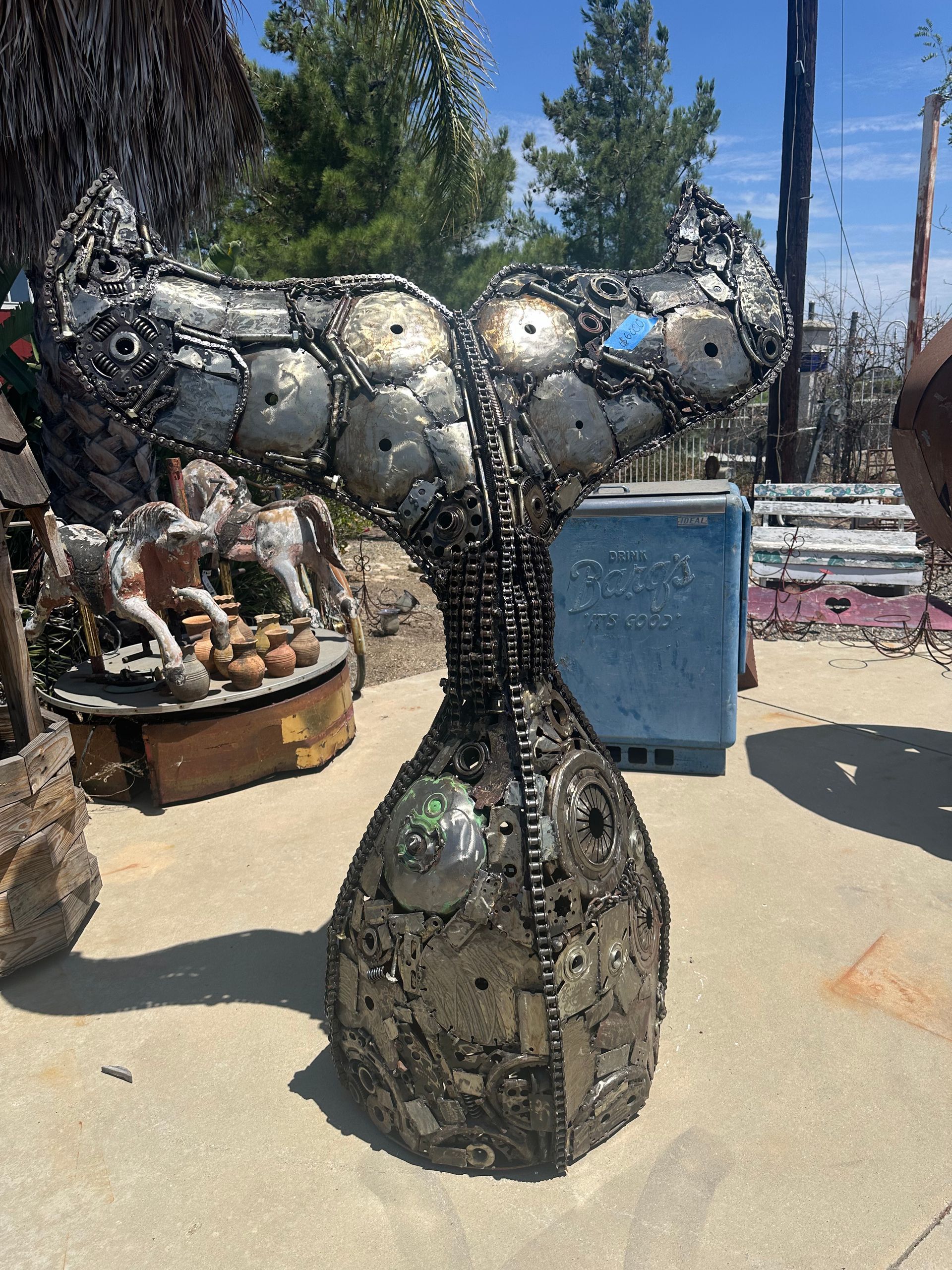 A large metal sculpture of a horse is sitting on a sidewalk.