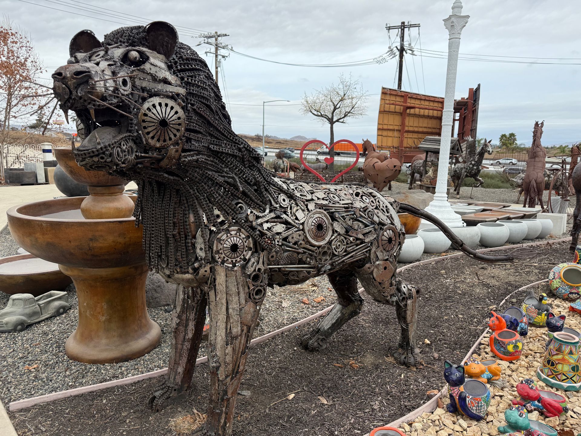 A statue of a lion made out of keys is standing in front of a fountain.