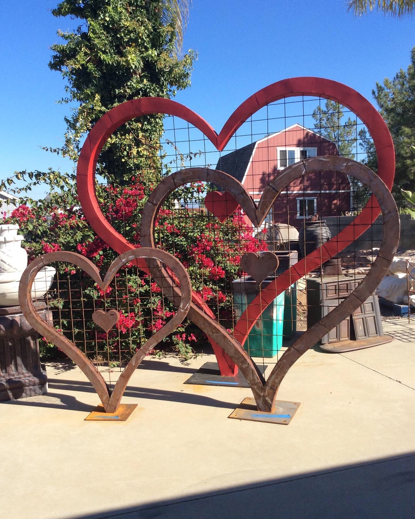A red barn is in the background of a sculpture of hearts
