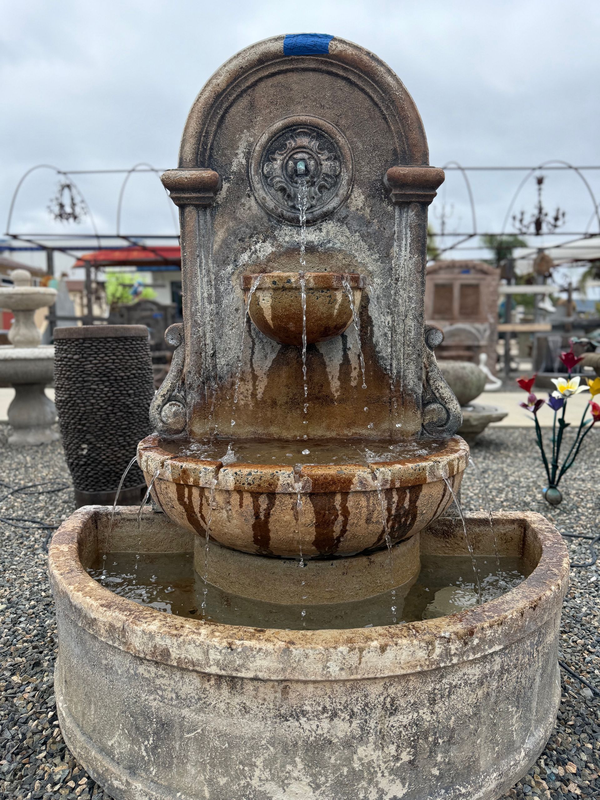 A large fountain is sitting on top of a gravel lot.