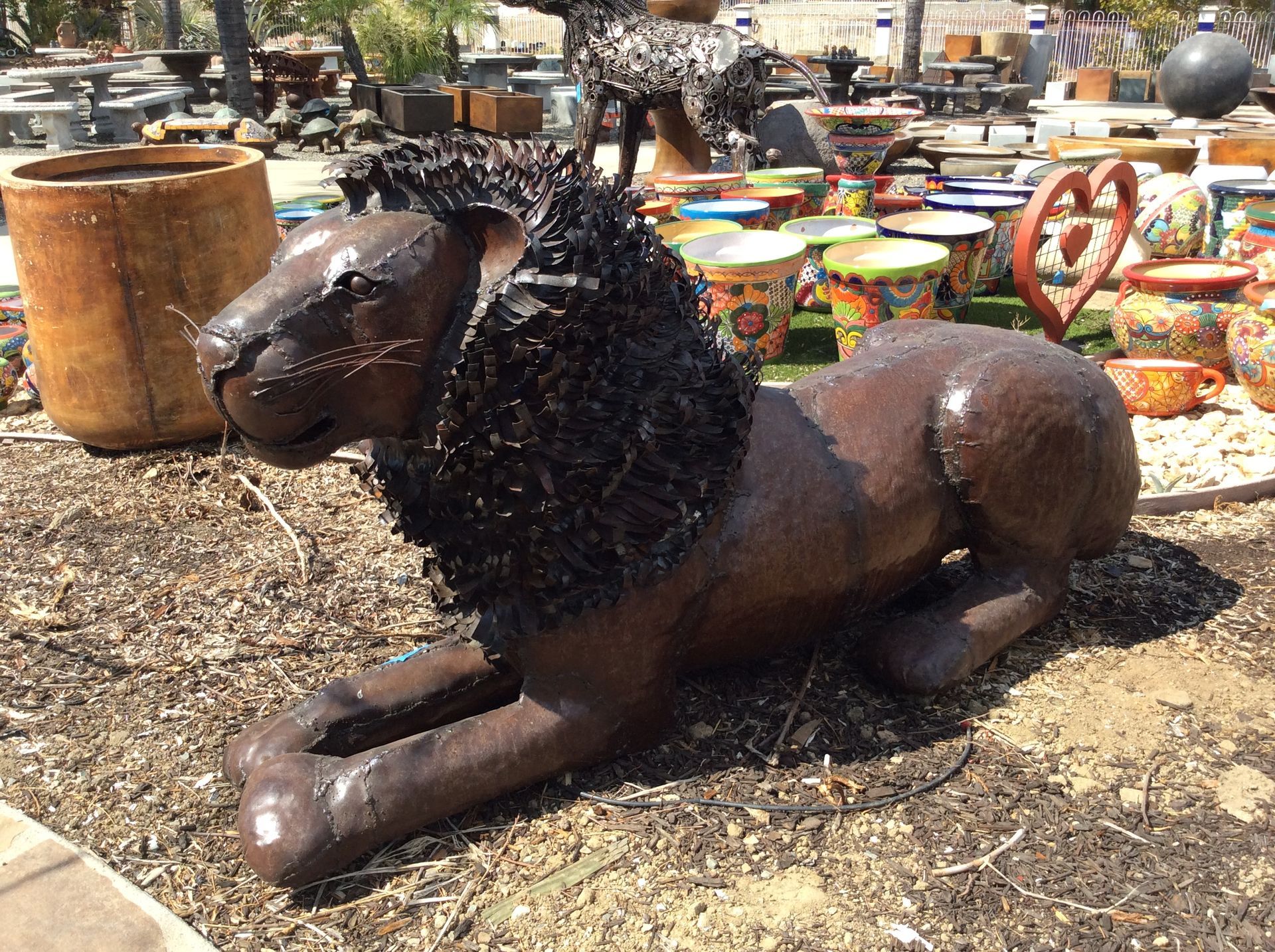 A statue of a lion laying down in the dirt