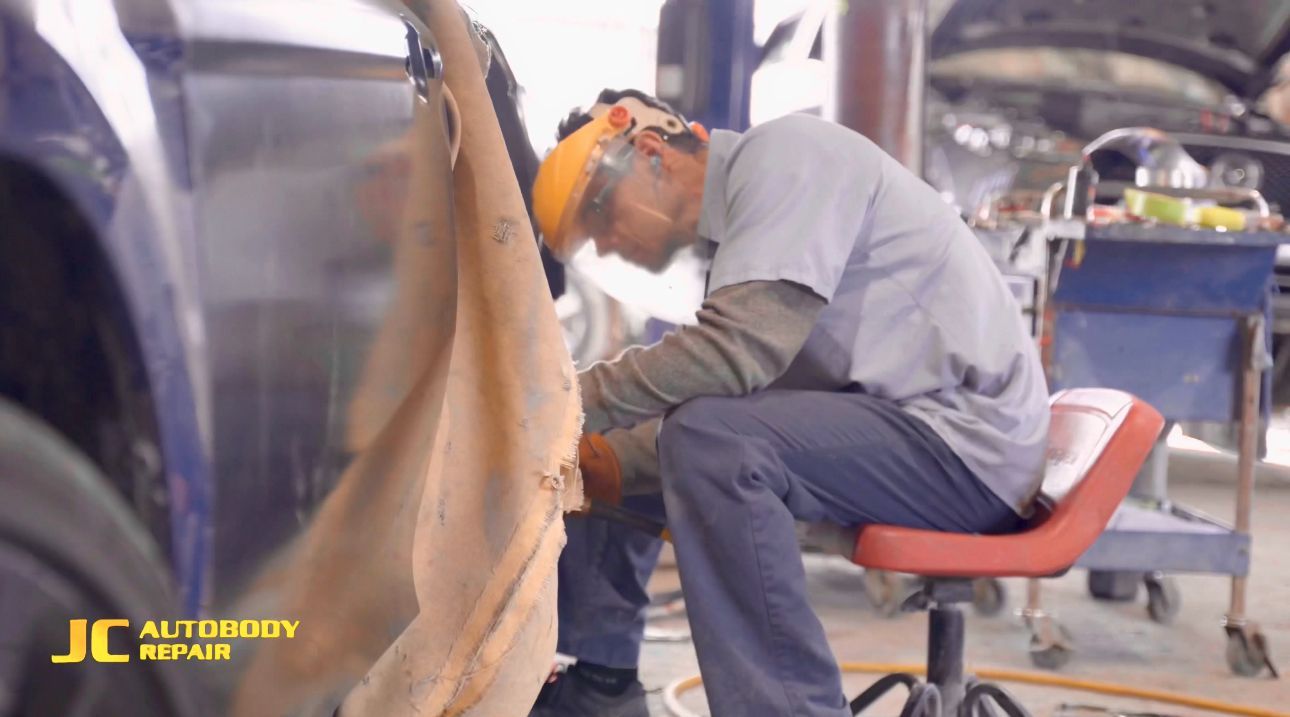 A man is sitting on a red chair working on a car.