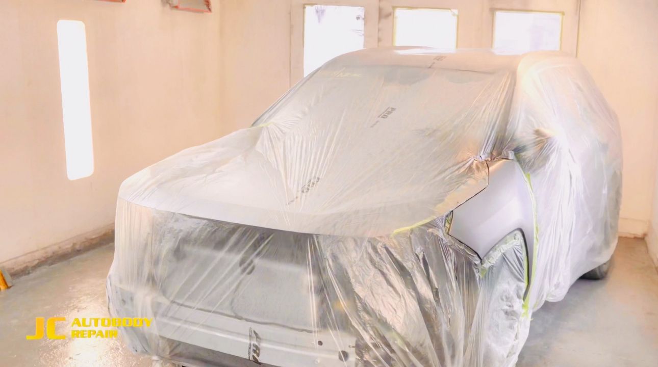 A car is covered in plastic wrap in a garage.