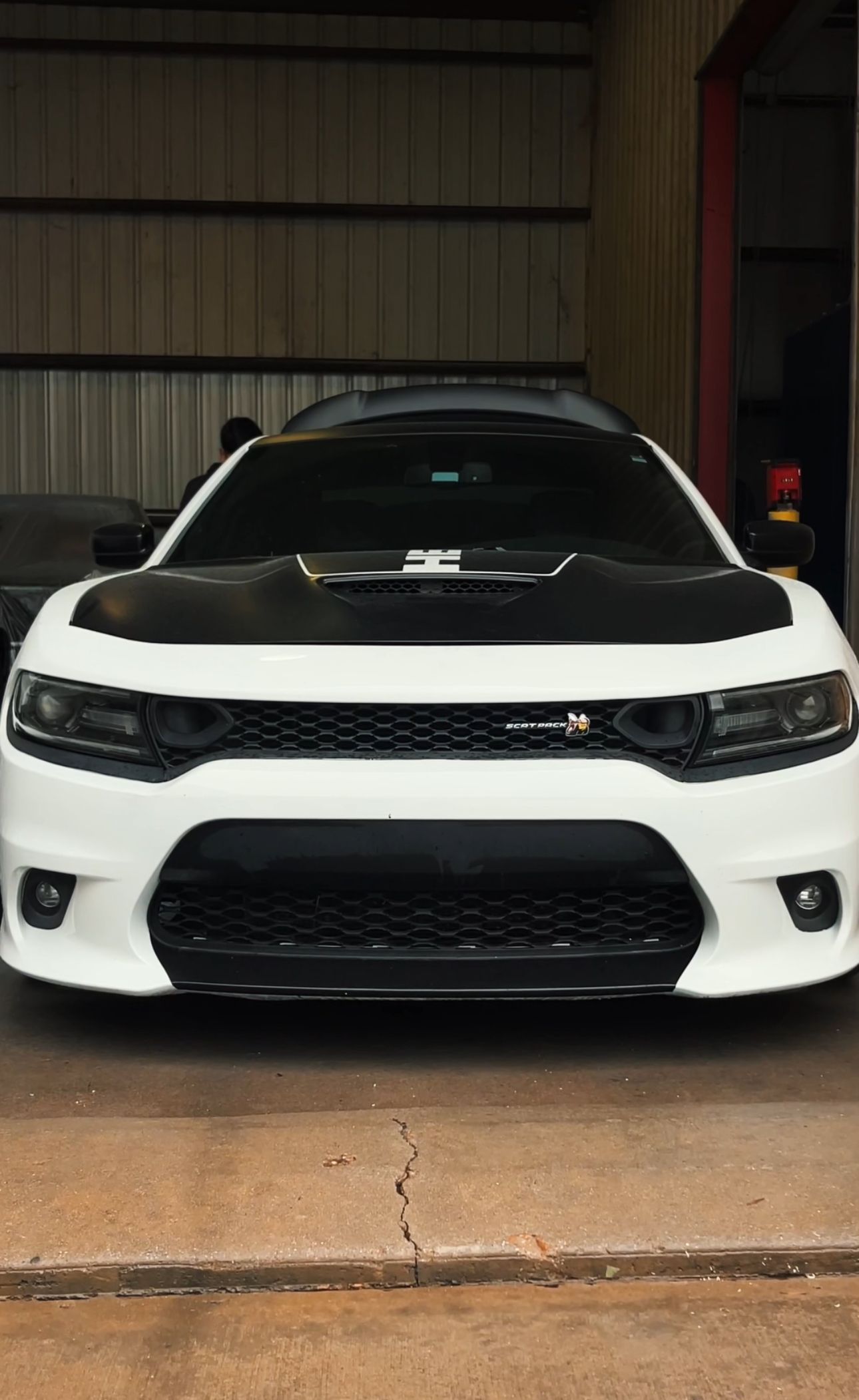 A white dodge charger is parked in a garage.