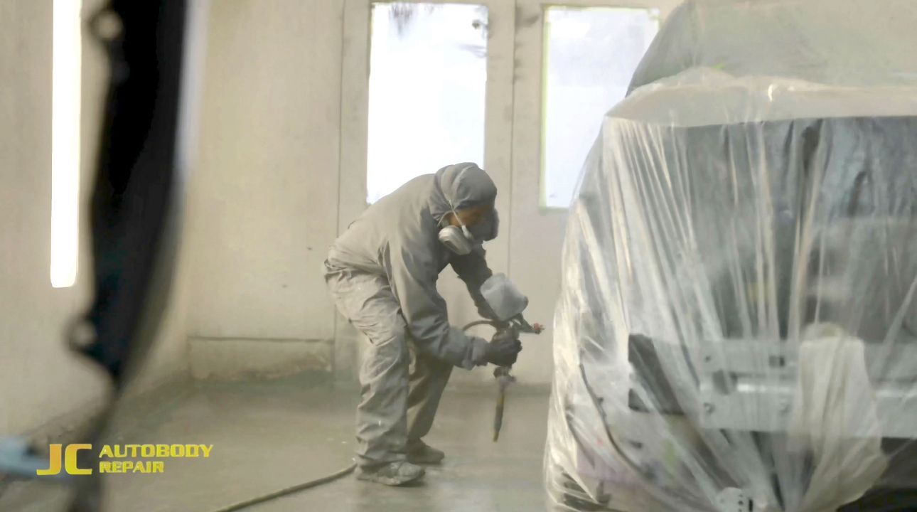 A man is spray painting a car in a garage.