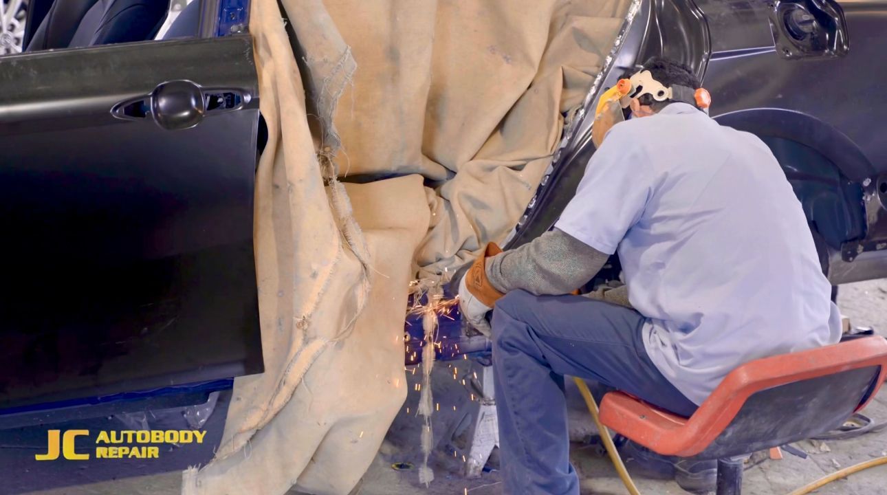 A man is welding a car door in a garage.