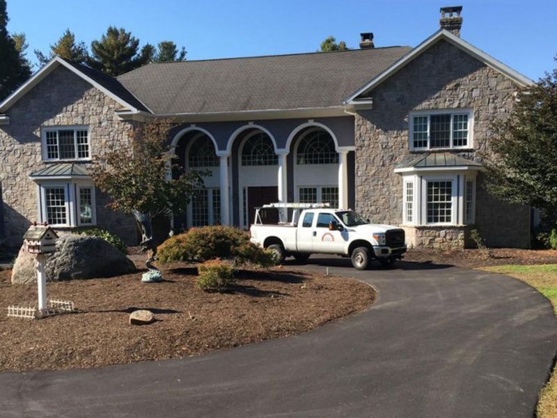 Large stone house with arched entry, white truck parked in driveway.