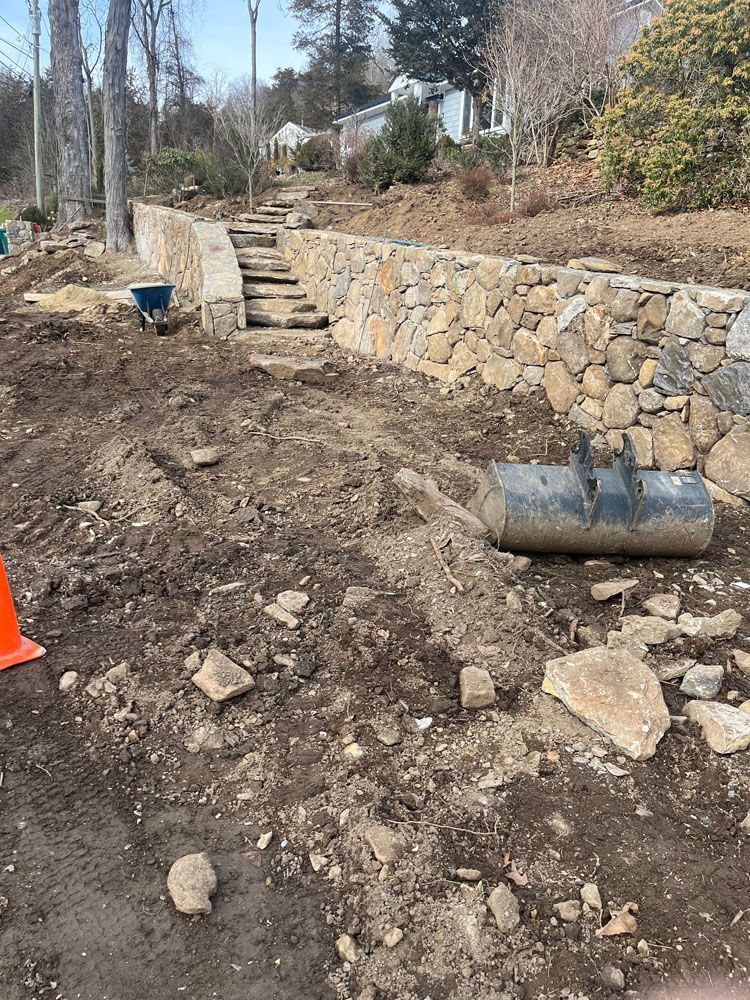 A stone wall is being built in the backyard of a house